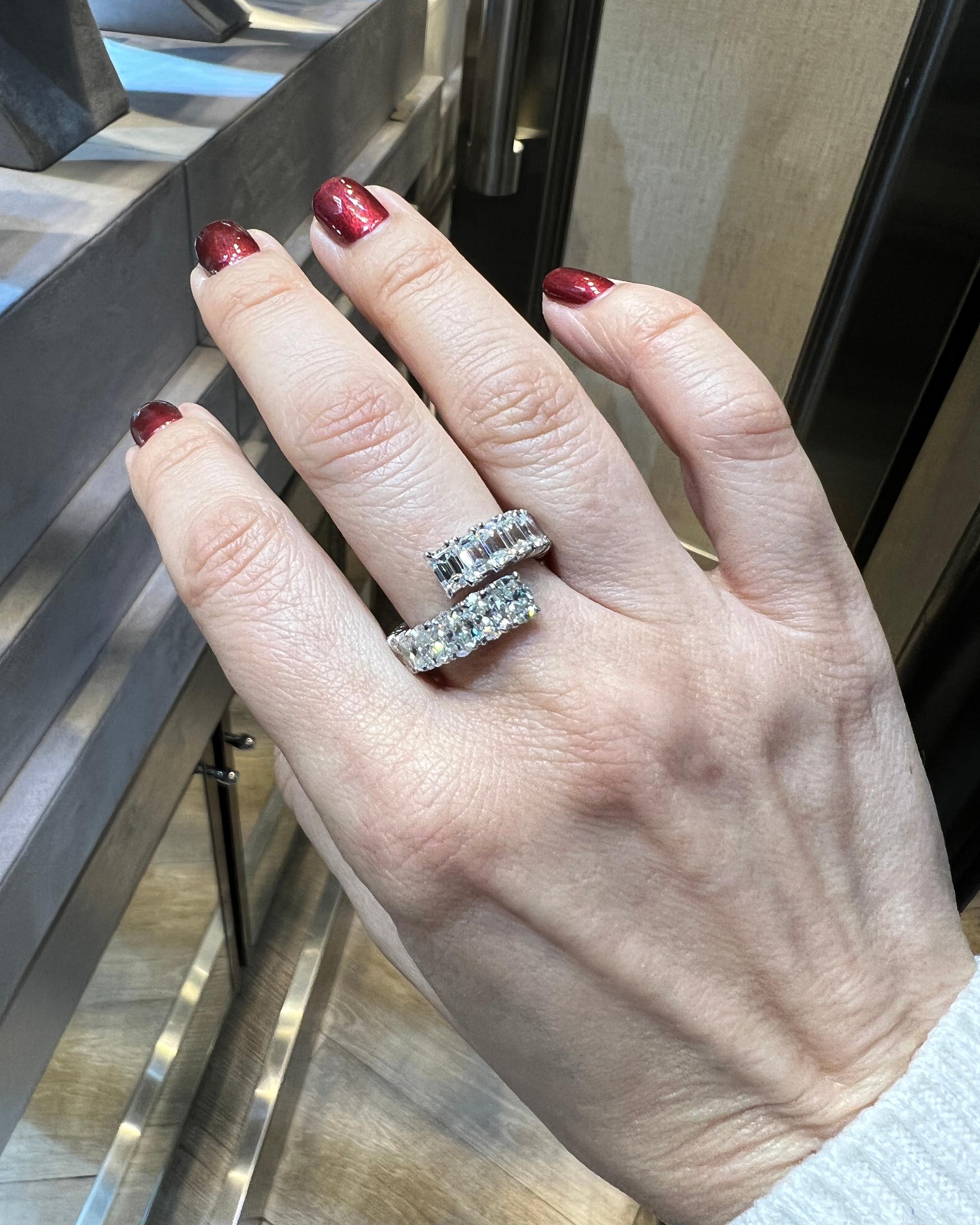 A diamond bypass ring comprising of 14 emerald-cut diamonds weighing 2.95 carats and 11 oval diamonds weighing 2.63 carats. Total weight is 5.58 carats.
The diamonds are not certified and are estimated as F-G colors, VS clarity.
Metal is 18k white