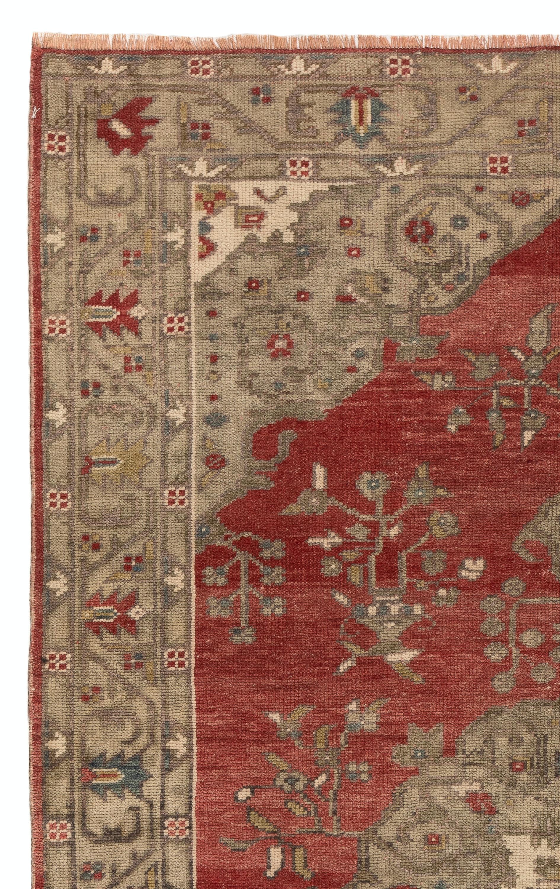 An antique hand-knotted Turkish 'Bergama' rug from West Anatolia made in the 1920s with soft medium wool pile. It features a large central medallion in stone beige color against a vermilion red field. Stylized floral bouquets in vases decorate the