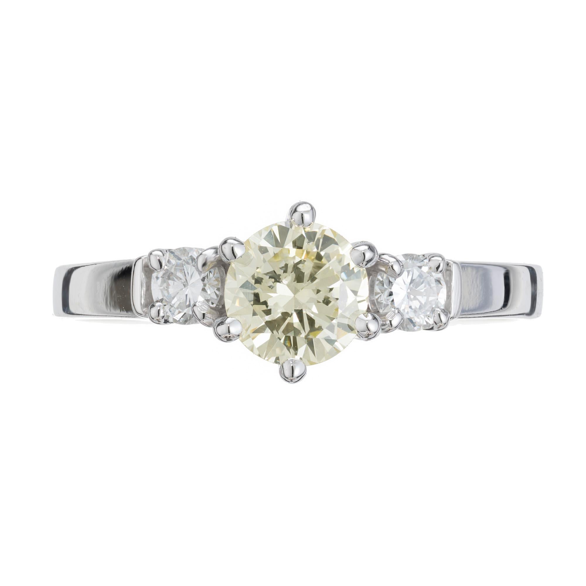 English Estate 1960'S fancy light yellow diamond engagement ring. .56cts round diamond center stone, set in a handmade 1960's handmade 18k white gold three-stone setting. Accented with 2 round cut side diamonds intended to accent the beautiful