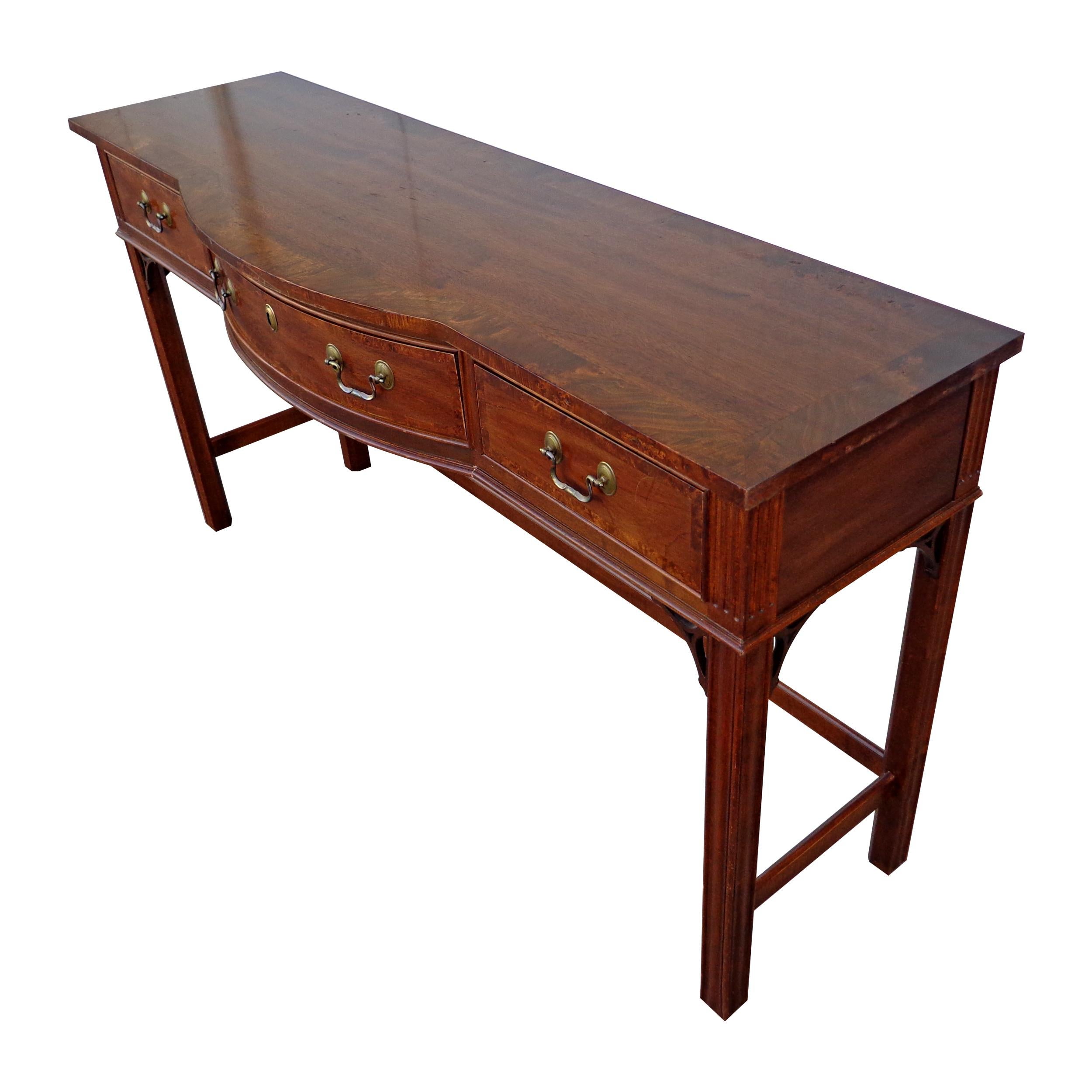 Sherrill console table featuring a birds eye maple inlay border on the top. Chippendale style base with bowed front.
Three drawers with brass pulls. Center drawer with lock. Measure: 56