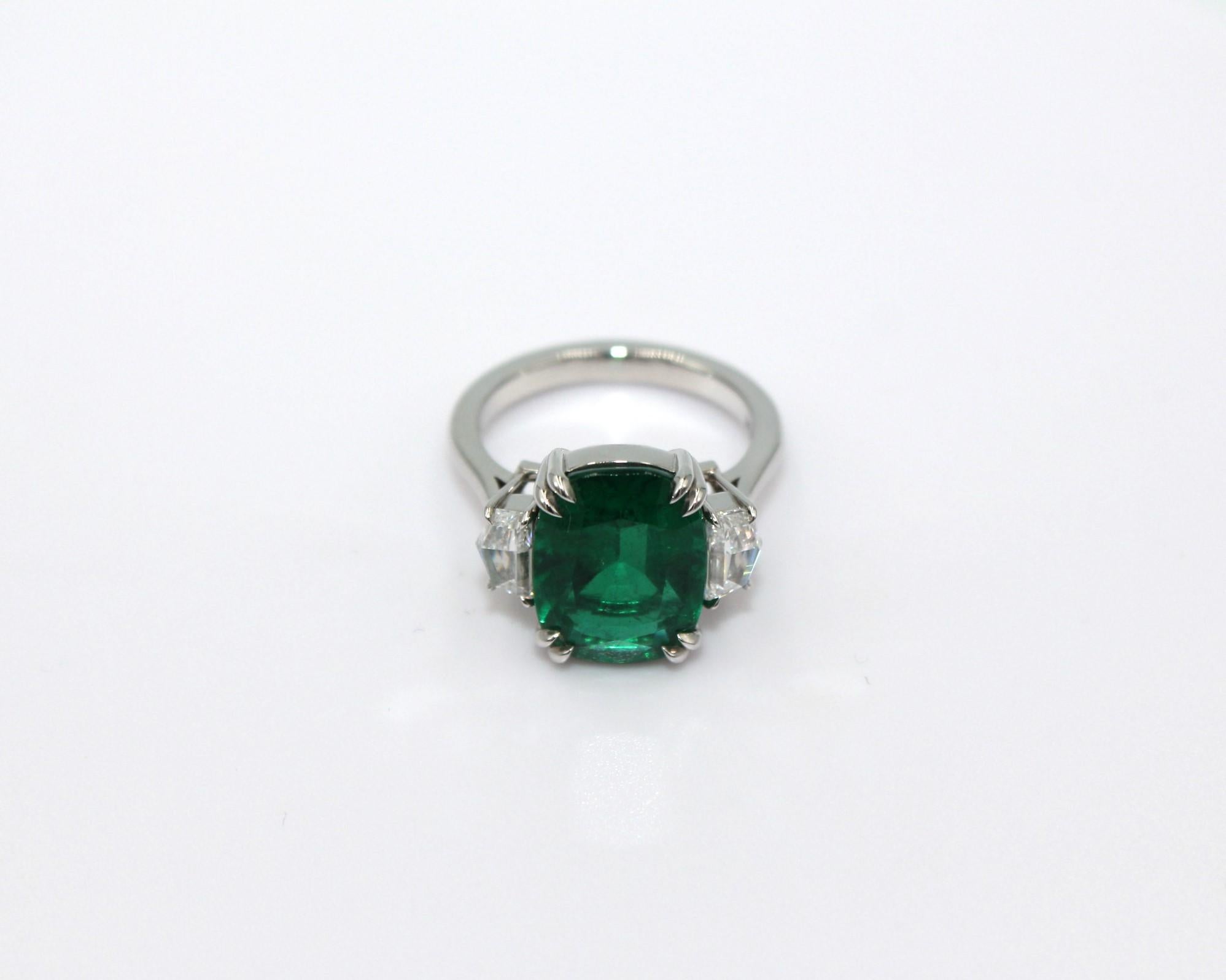 Three-stone ring with 5.60 carats cushion Zambian Emerald and paired Cadillac shape diamonds, totaling a diamond weight of 0.86 carats. 

This stunning Emerald Diamond Ring will highlight your elegance and uniqueness. 

Item Details:
- Type: Ring
-
