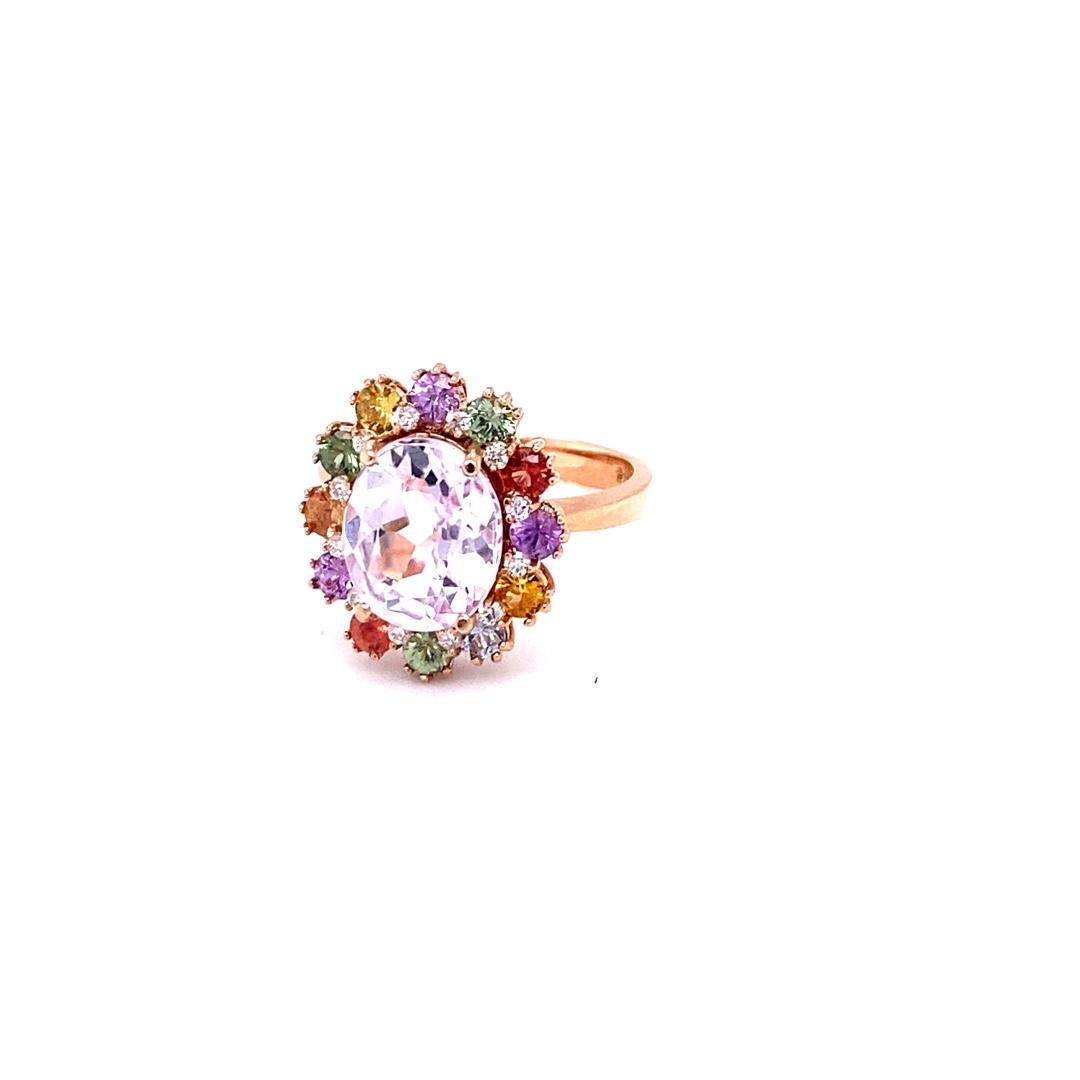 This ring has an Oval Cut Kunzite that measures at 9 mm x 11 mm and is 3.88 carats. It also has 12 Multi Colored Sapphires that measure at 1.58 carats and 12 Round Cut Diamonds that weigh 0.14 carats. The total carat weight of the ring is 5.60