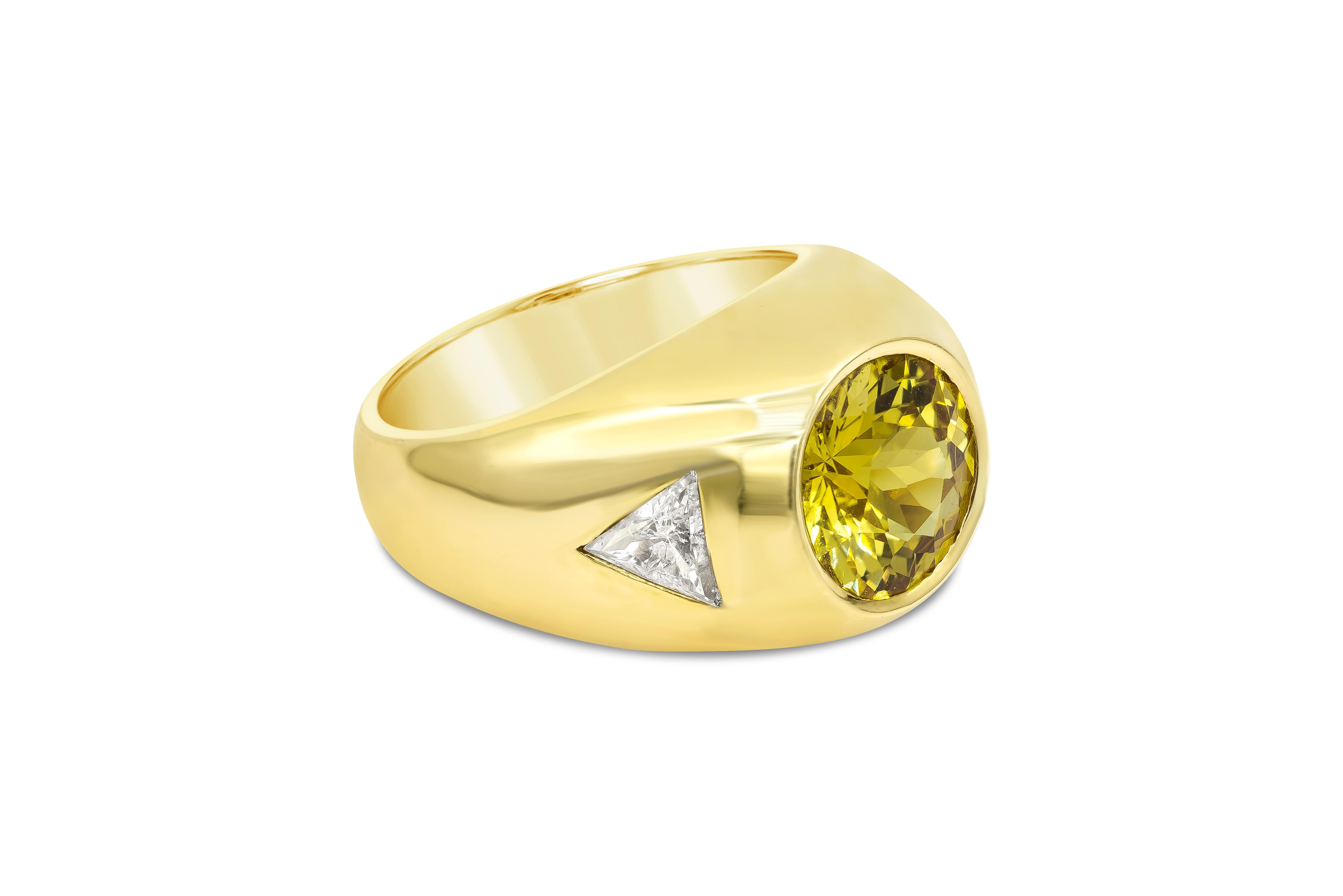 Features a 5.61 carat round yellow sapphire set flushed in a thick and wide setting made in 18k yellow gold. Accenting the ring are two trillion diamonds weighing 1.01 carats total. Size 9.25 US (Sizable upon request).

Style available in different