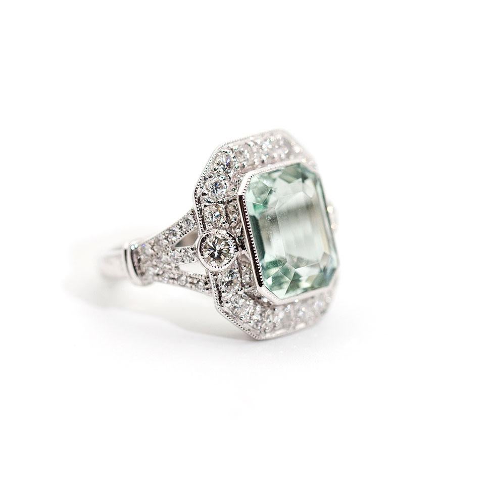 Forged with love and devotion in 18 carat white gold, this vintage-inspired halo ring is absolutely stunning. Branching shoulders encrusted with shimmering round brilliant cut diamonds rise up to an enchanting gallery featuring an alluring