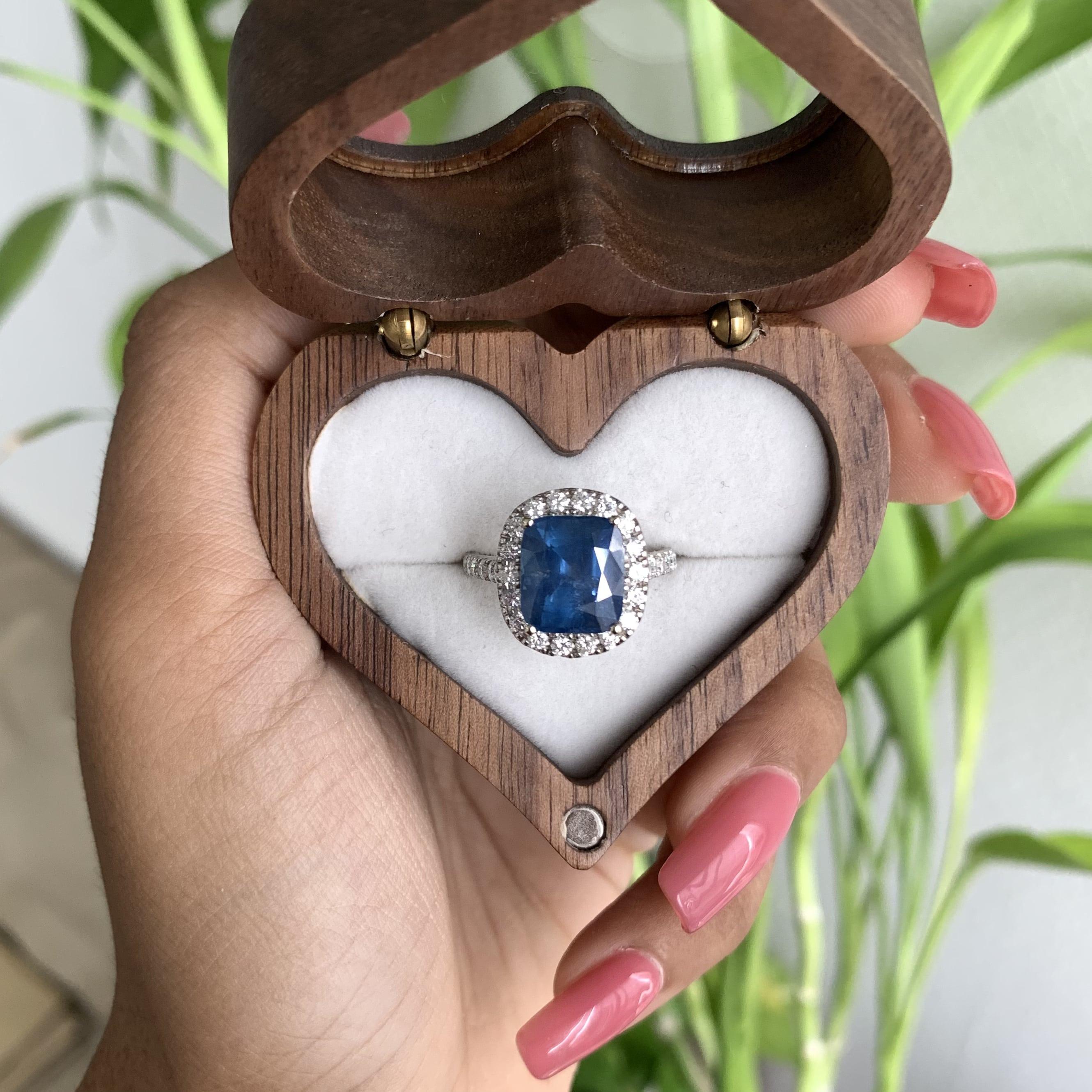 A true masterpiece that captures the essence of elegance and sophistication. This enchanting piece of jewellery boasts a magnificent centerpiece - a stunning 5.68 carat teal blue cushion-cut sapphire, radiating with a captivating teal hue that