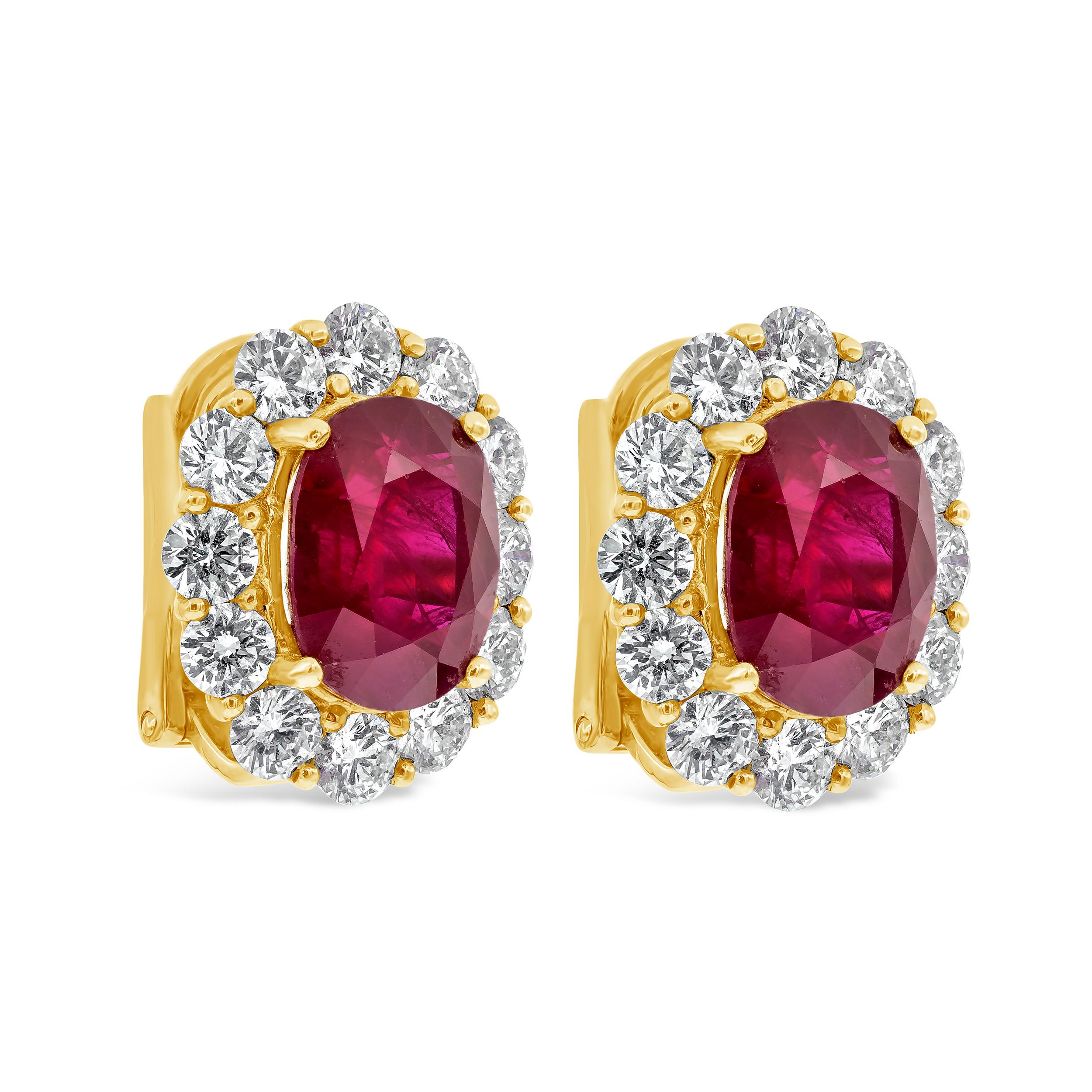 A pleasing pair of gemstone earrings features two color rich GIA Certified oval cut heated rubies weighing 5.69 carats total, surrounded by a single row of brilliant round diamonds in a halo design weighing 2.14 carats total. Made in 18K Yellow