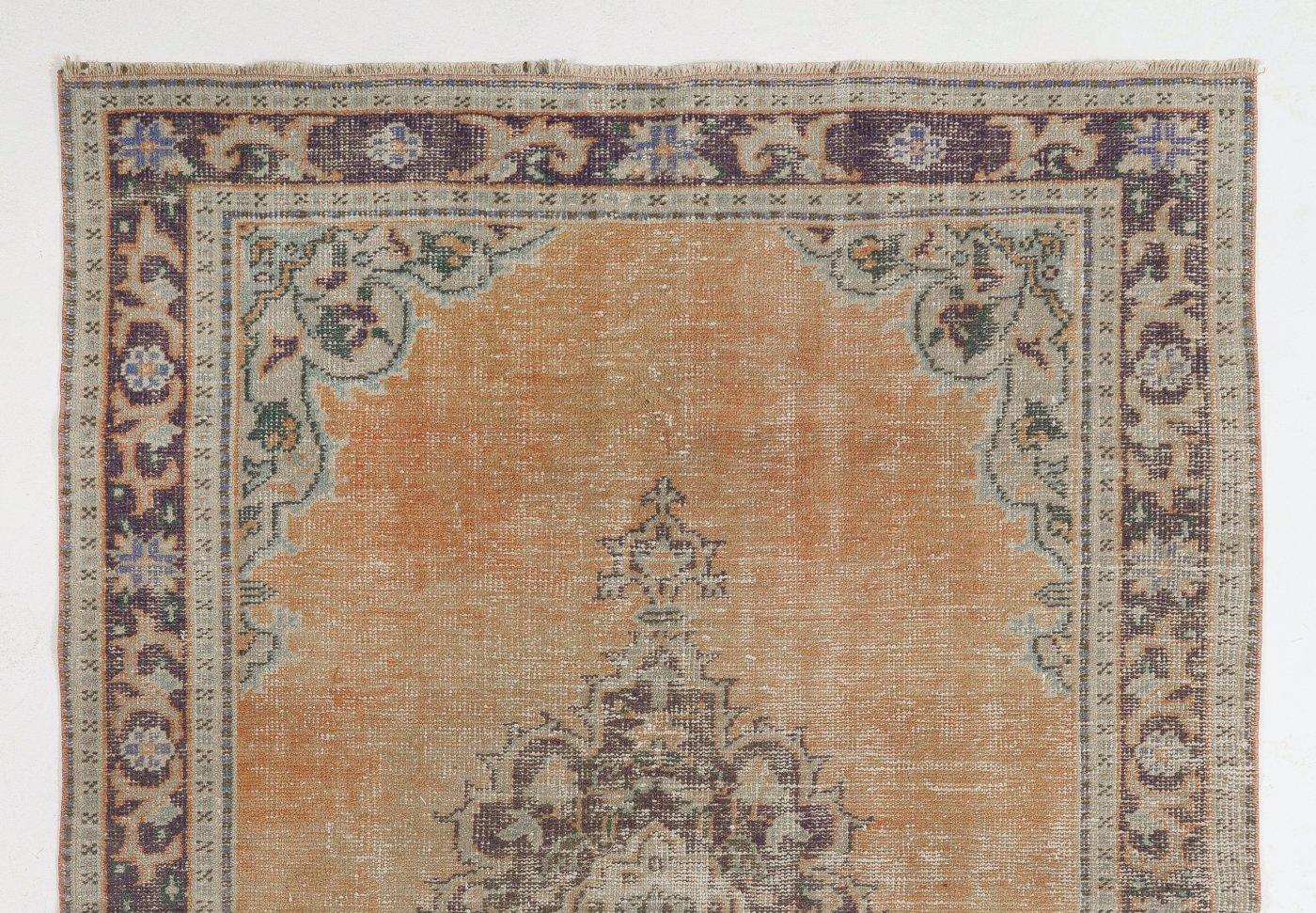 A vintage hand-knotted rug from Central Turkey with distressed low wool pile on cotton foundation, featuring a central medallion against a plain field in faded tomato red. The rug is in good condition, sturdy, as clean as a brand new rug (deep