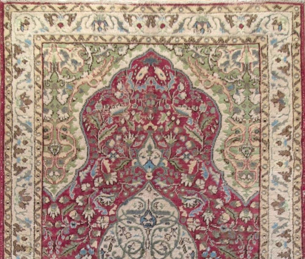 This vintage hand knotted mid-20th century area rug from Western Anatolia boasts a curvilinear medallion in ivory against a field in burgundy, filled densely with swirling leafy vines and floral heads in bright light blue, sage green and ivory. The