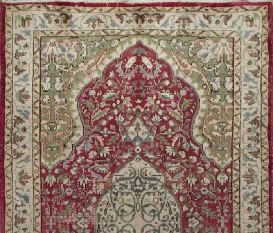 This vintage hand knotted mid-20th century area rug from Western Anatolia boasts a curvilinear medallion in ivory against a field in burgundy, filled densely with swirling leafy vines and floral heads in light blue, sage green and ivory. The four