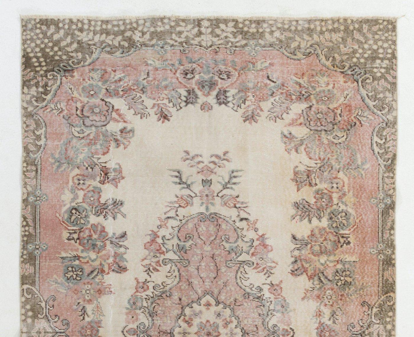 A hand-knotted vintage Turkish area rug. The rug features a floral medallion design in a field decorated with floral motifs. It has low distressed wool pile on cotton foundation, is in very good condition, sturdy and clean as a brand new rug.