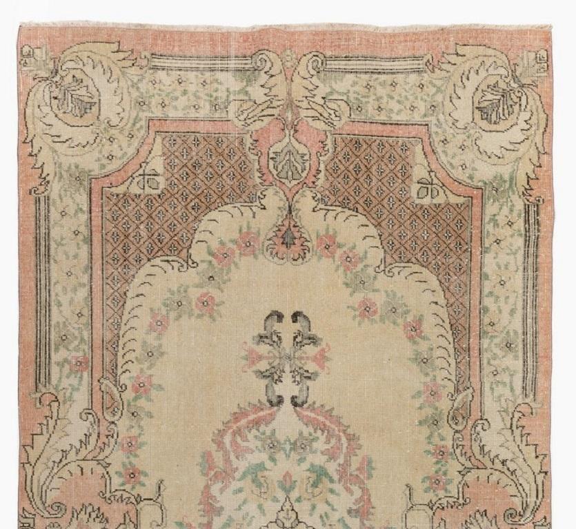 A finely hand-knotted vintage Turkish carpet from the 1960s featuring a French-Aubusson inspired design of a floral medallion, surrounded by realistic looking floral wreaths as well as latticed corner pieces and lush, large cartouches at borders, in