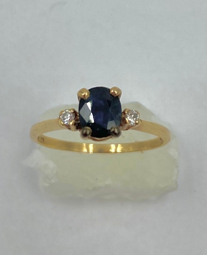 A lovely Antique Sapphire and Diamond Wedding Engagement Stacking Ring in 14 Karat Yellow Gold.  The Sapphire is a fine blue oval faceted sapphire of .57 Carats.  On either side of the Sapphire are two sparkling white Diamonds.  The Sapphire and