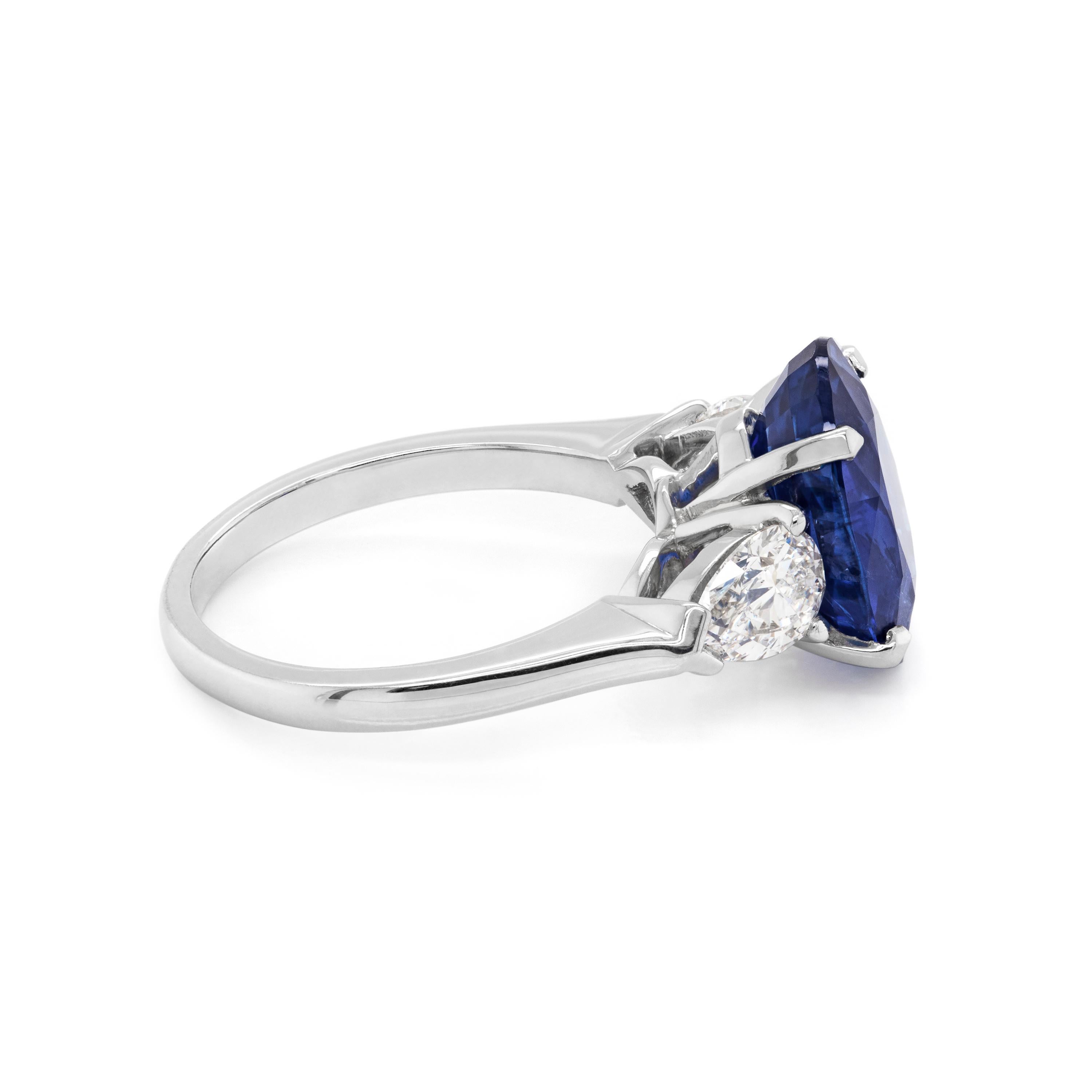 Une bague de fiançailles absolument exquise mettant en vedette un saphir ovale bleu royal pesant 5.70 carats serti dans une monture à quatre griffes, à dos ouvert. Cette pierre incroyable est accompagnée d'un diamant en forme de poire de chaque