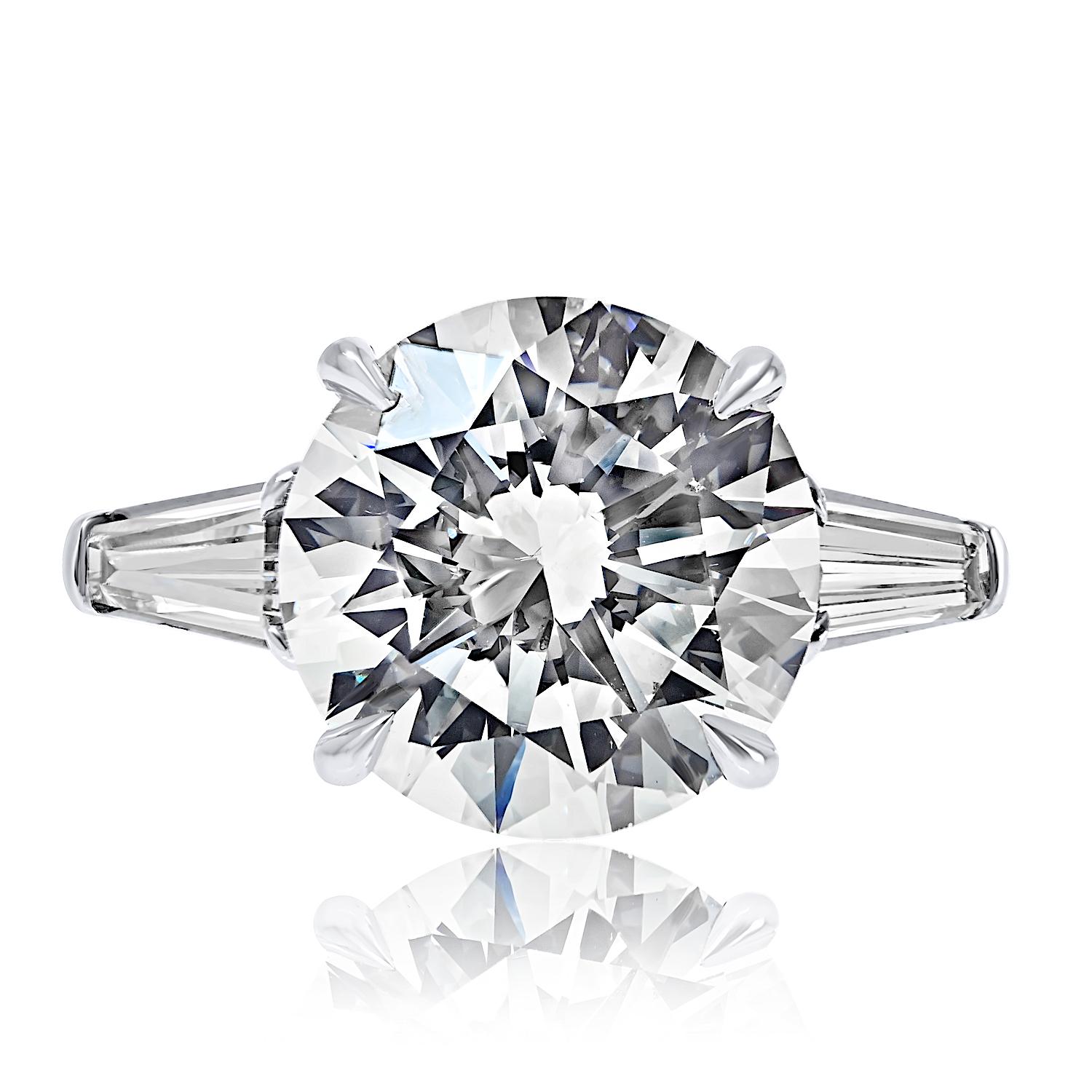 Une bague de fiançailles élégante et intemporelle, ornée d'un superbe diamant central rond de 5,70 carats taillé en brillant, certifié par le GIA. La pierre centrale naturelle est de couleur I et de pureté SI1, avec une taille exceptionnelle Triple