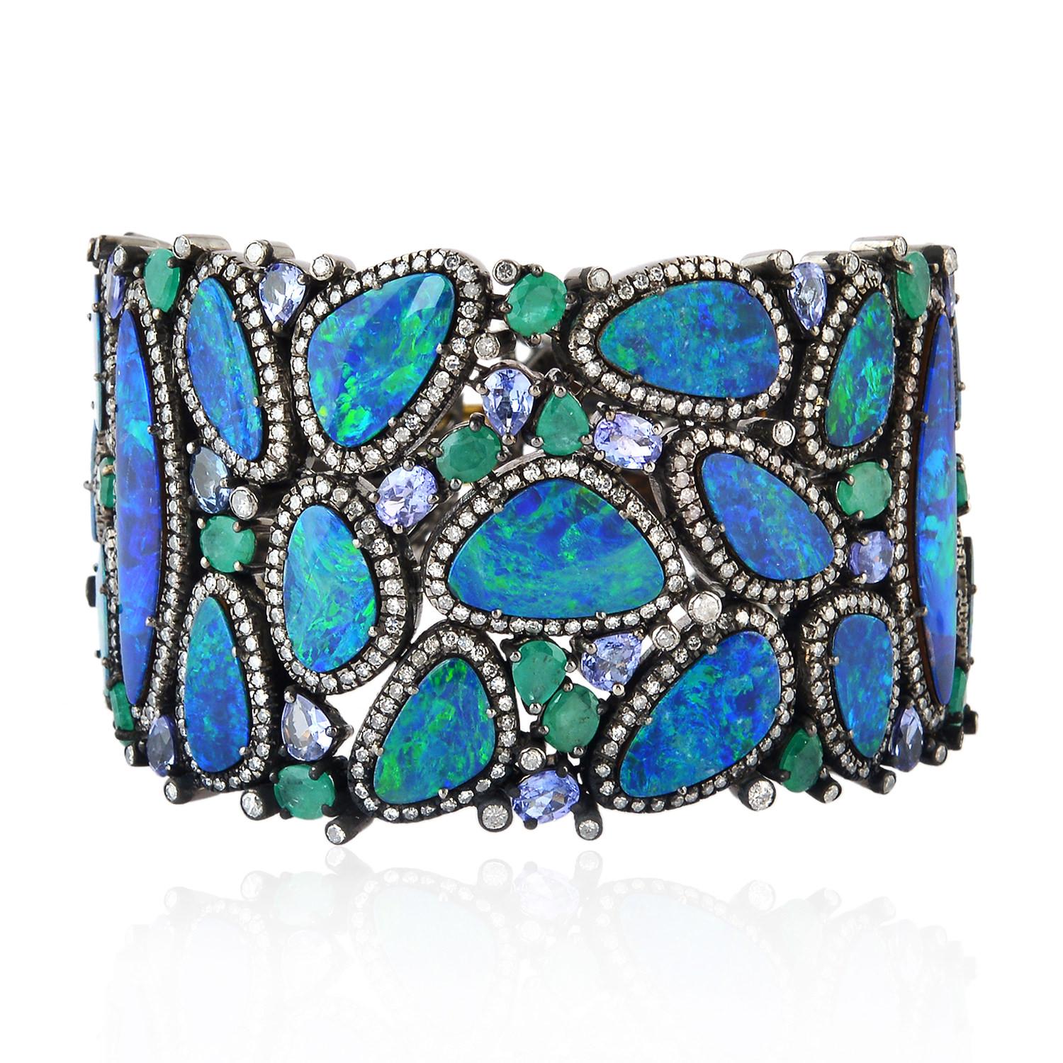 A stunning bracelet cuff is handmade in 18K gold and sterling silver. It is set in 7.97 carats emerald, 57.12 carats opal doublet, 7.42 carats tanzanite and 7.27 carats diamonds. Pair this with your favorite evening dress for a red carpet look.