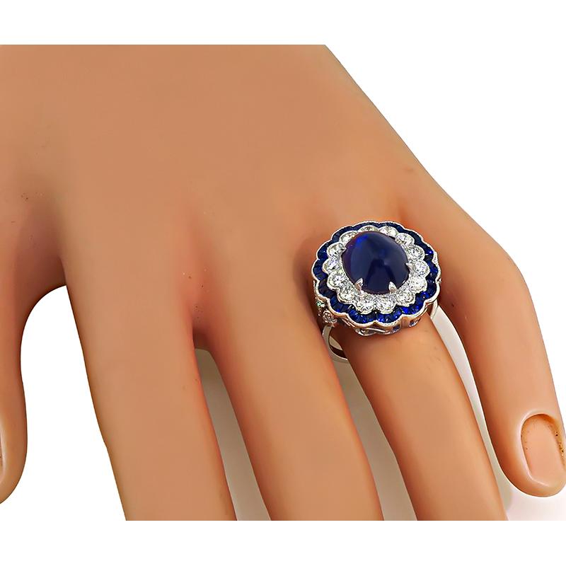 This is an amazing 18k white gold ring. The ring is centered with a lovely sugarloaf cut sapphire that weighs approximately 5.71ct. The center sapphire is accentuated by sparkling round cut diamonds and French Cut sapphires that weigh approximately