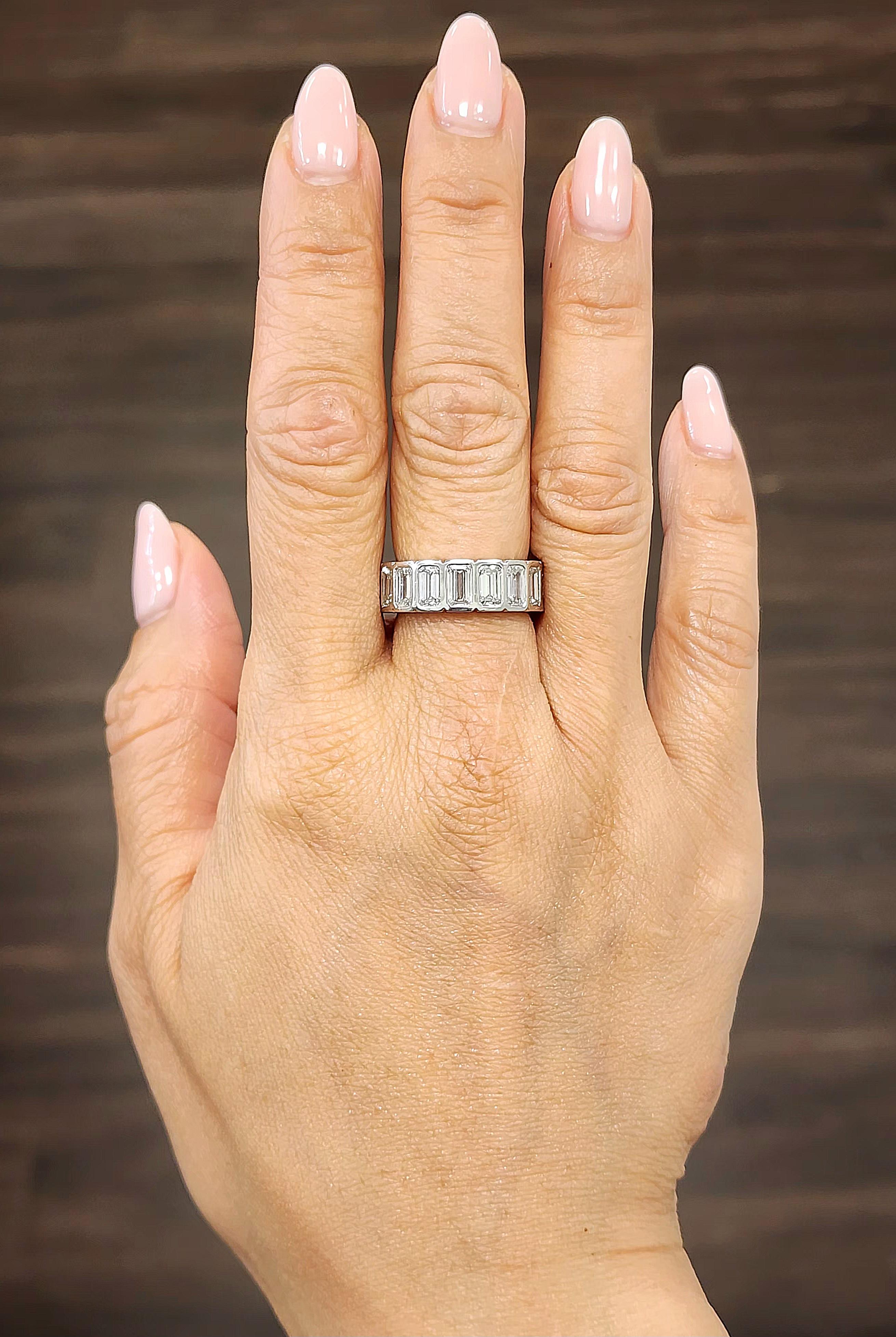 This beautiful emerald cut bezel set diamond eternity ring is a magnificent addition to any wardrobe. The ring features 17 5x3 emeralds boasting a color of E/F and VS in clarity and set in platinum.