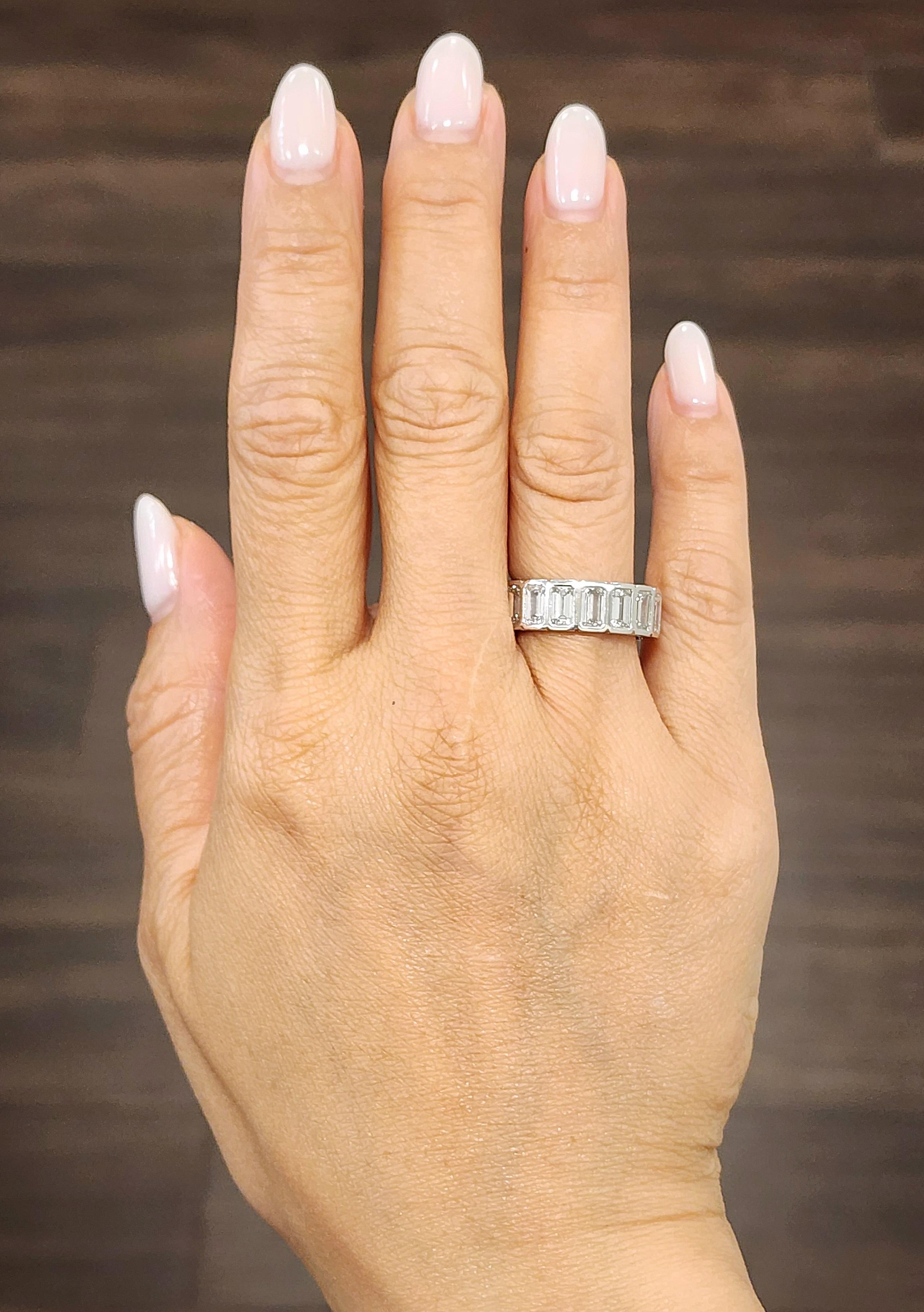 This exquisite eternity ring showcases 17 emerald-cut diamonds, each measuring 5x3 mm and bezel-set in platinum for a sleek, modern look. The diamonds are graded E/F in color and VS1/VS2 in clarity, offering exceptional brilliance and