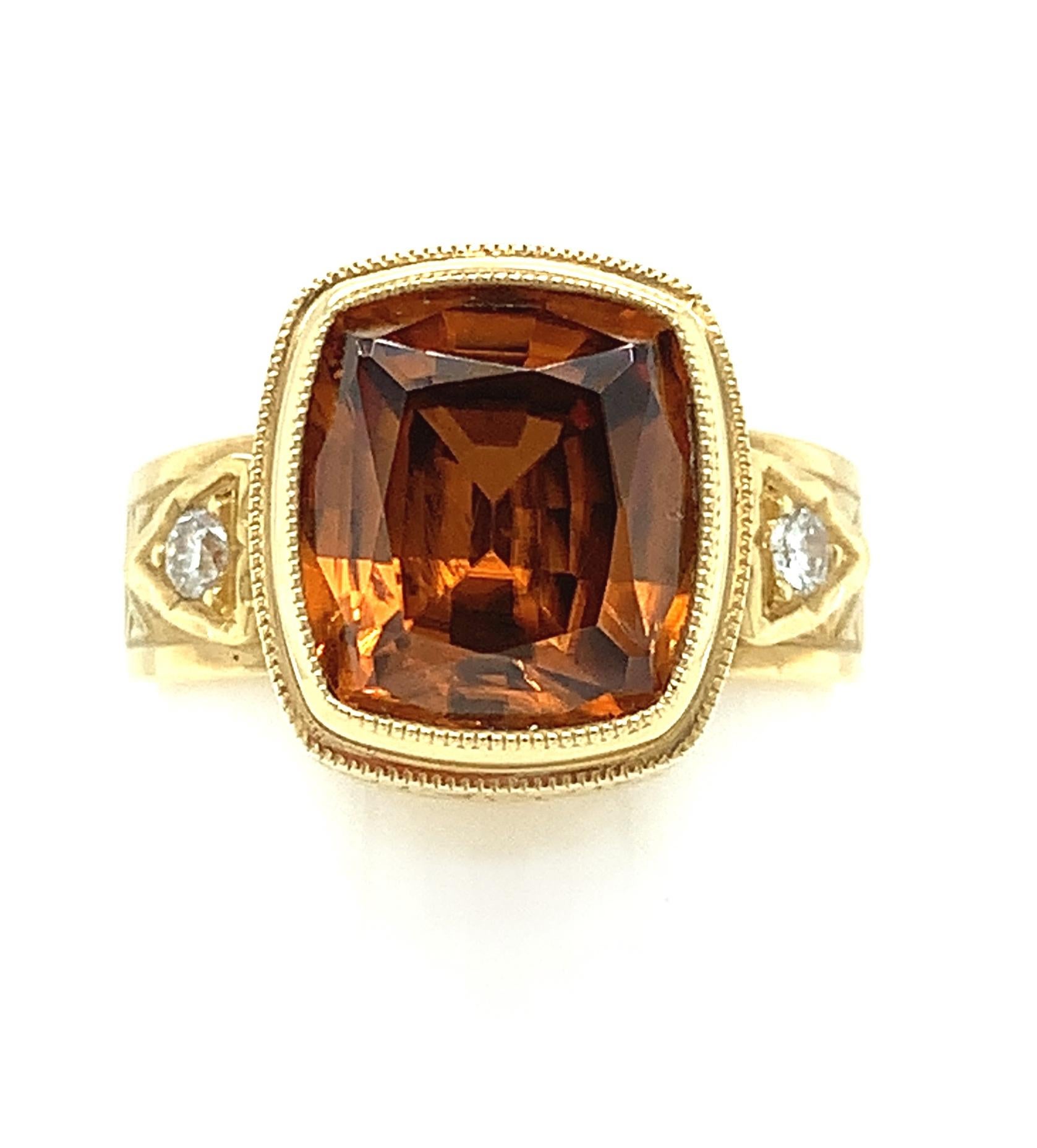 This meticulously detailed ring is a stunning statement piece! The warm tones of the vibrant, golden-orange zircon and the rich 18k yellow gold bezel are reminiscent of a sunset. The wide band complements the cushion shape of the zircon, and