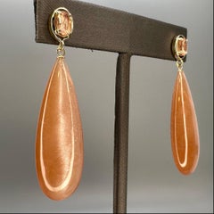 57.43k Tanzanian sunstone drop, oval cut sunstone, and 14k yellow gold earrings