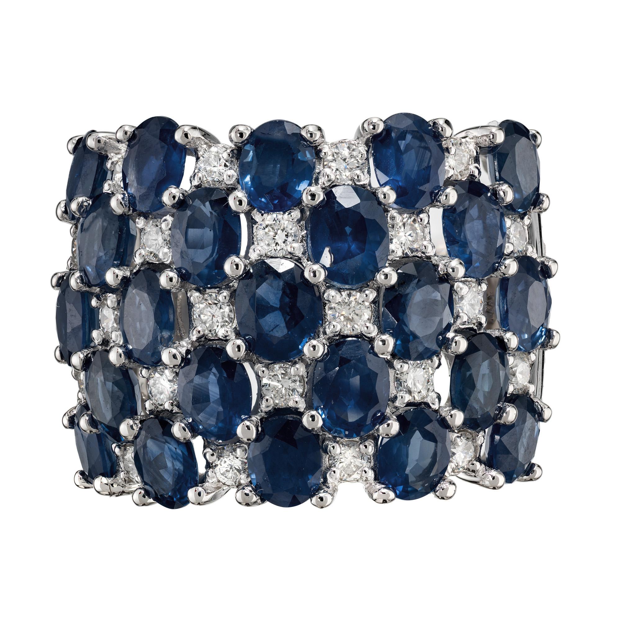 Uncommonly wide sapphire and diamond cluster ring. 18mm 14k white gold setting. Adorned with 23 striking oval deep blue sapphires with an approximate total weight of 5.75cts. 22 round brilliant cut diamonds intertwine with the sapphires creating a