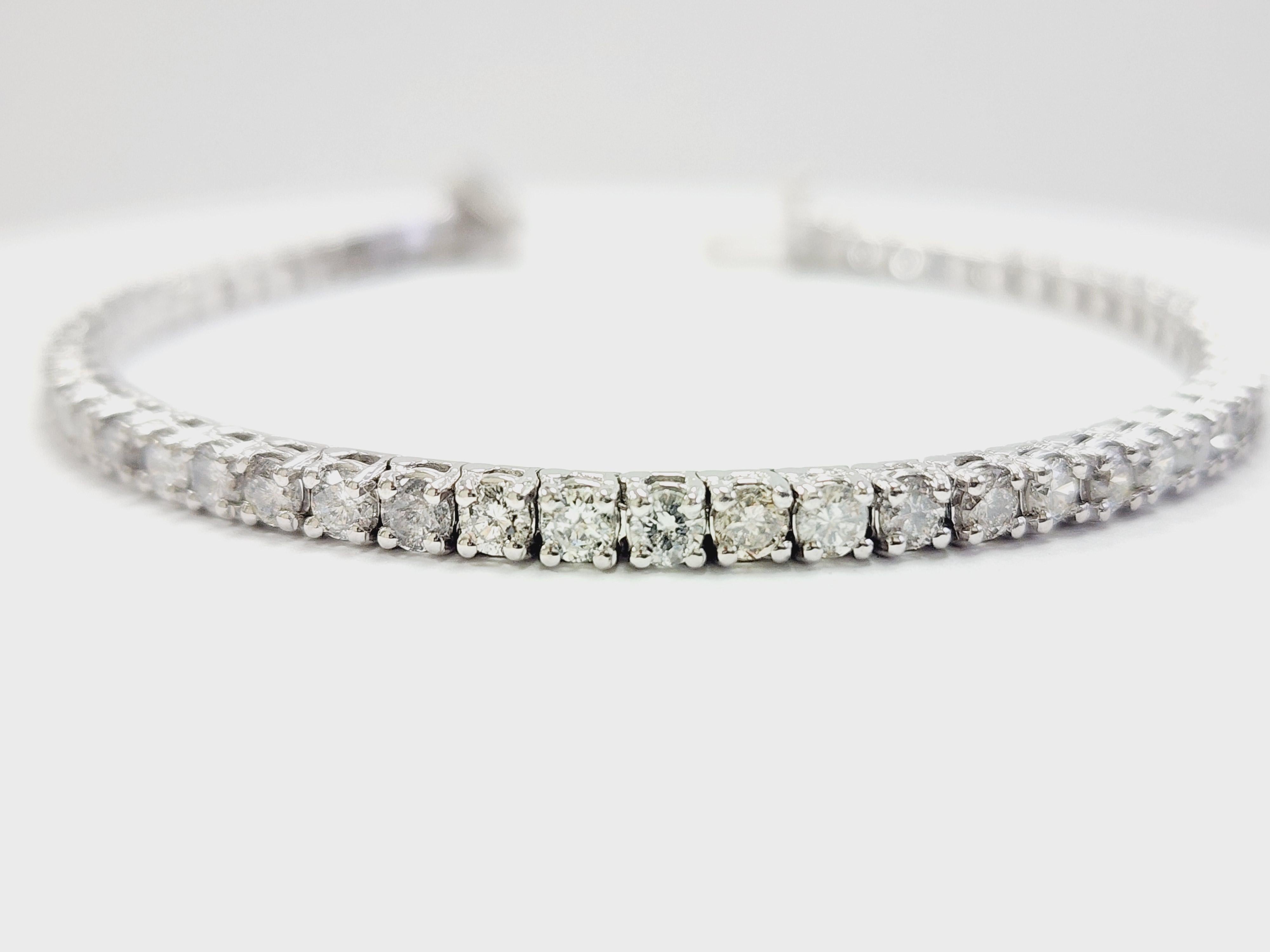 A timeless symbol of elegance, this classic tennis bracelet features 5.77 carats of natural round brilliant-cut diamonds, expertly set in 14 karat white gold. The bracelet measures 7 inches in length and 3.3 mm in width, showcasing a continuous line