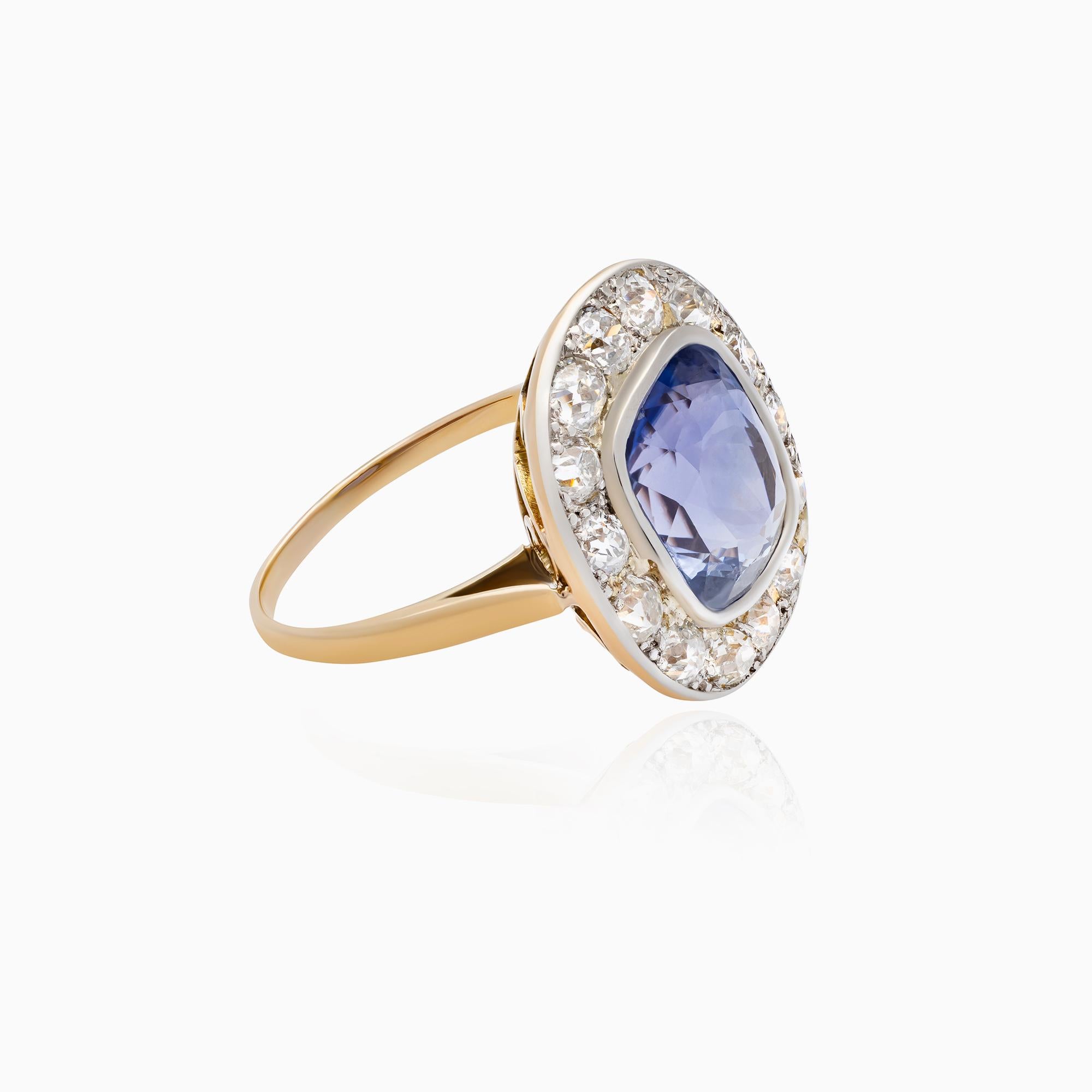 Bague en saphir de 5,77 carats à taille coussin en or jaune 14K avec 1,33 carats de diamants taille ancienne dans un halo d'inspiration vintage. Le saphir naturel présente une élégante teinte bleu-violet et une belle transparence. Sa taille en