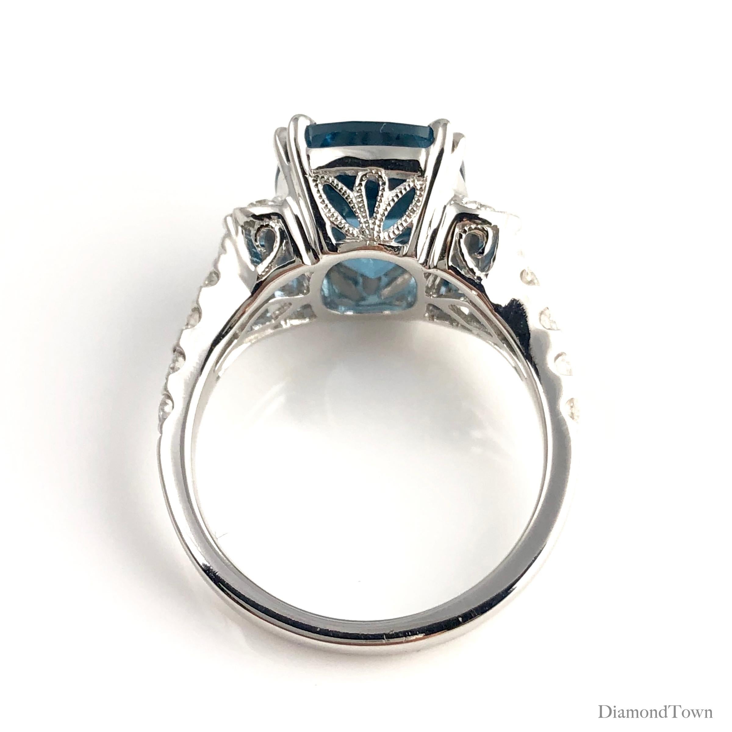 This gorgeous ring features a 5.79 carat cushion cut London Blue Topaz center, flanked by marquise cut diamonds on each side, as well as graduated round diamonds extending down the side shank. Intricate milgrain work makes this ring shine from all