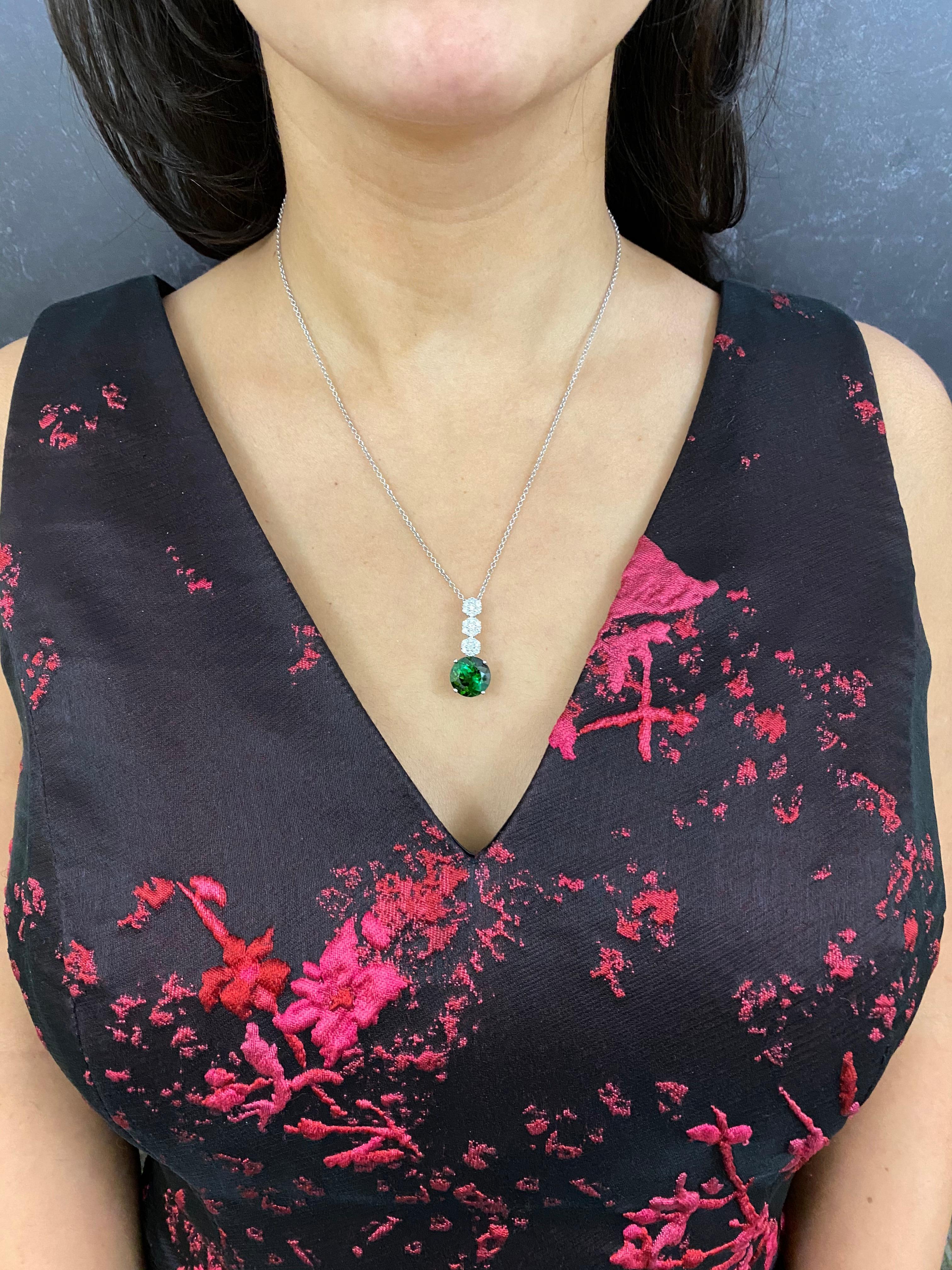 Material: 14k White Gold 
Center Stone Details: 1 Round Green Tourmaline at 5.79 Carats- Measuring 11.5 mm
Diamonds: 21 Brilliant Round White Diamonds at 0.51 Carats. SI Clarity /  H-I Color

Fine one-of-a-kind craftsmanship meets incredible quality