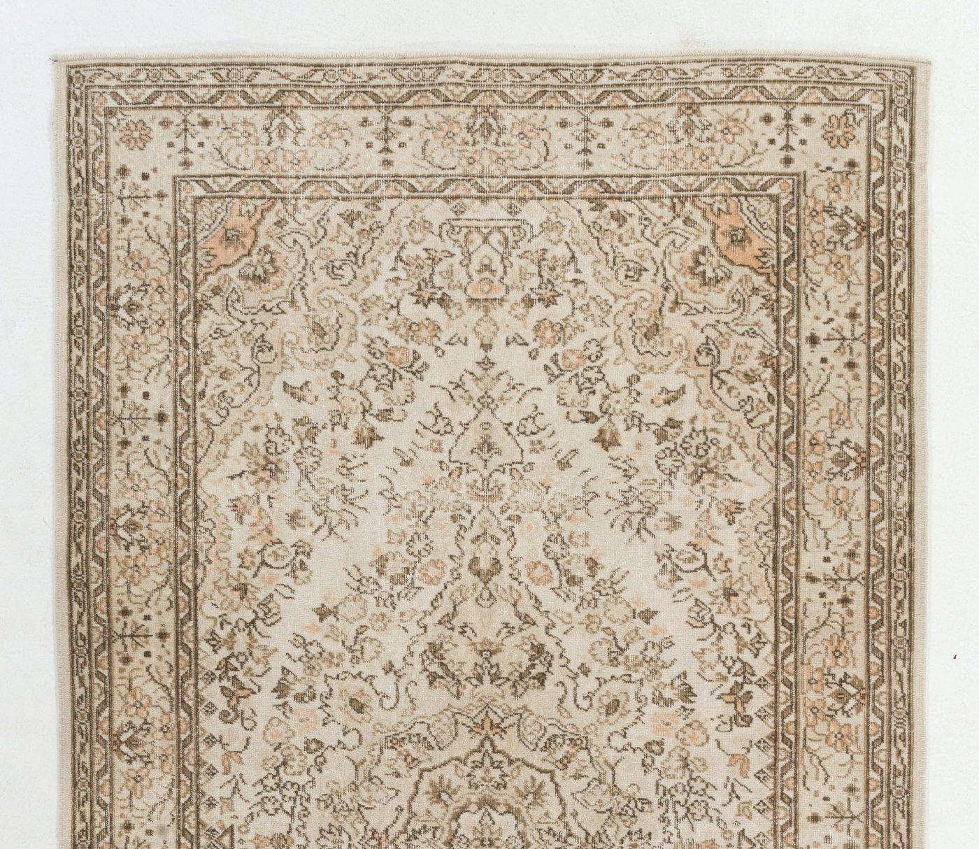 Vintage Turkish area rug hand-knotted in the 1960s with Finely hand-knotted with low wool pile on cotton foundation. The rug has an intricate floral design with a medallion at the center, in soft peach and swamp mud green against an ivory field. It