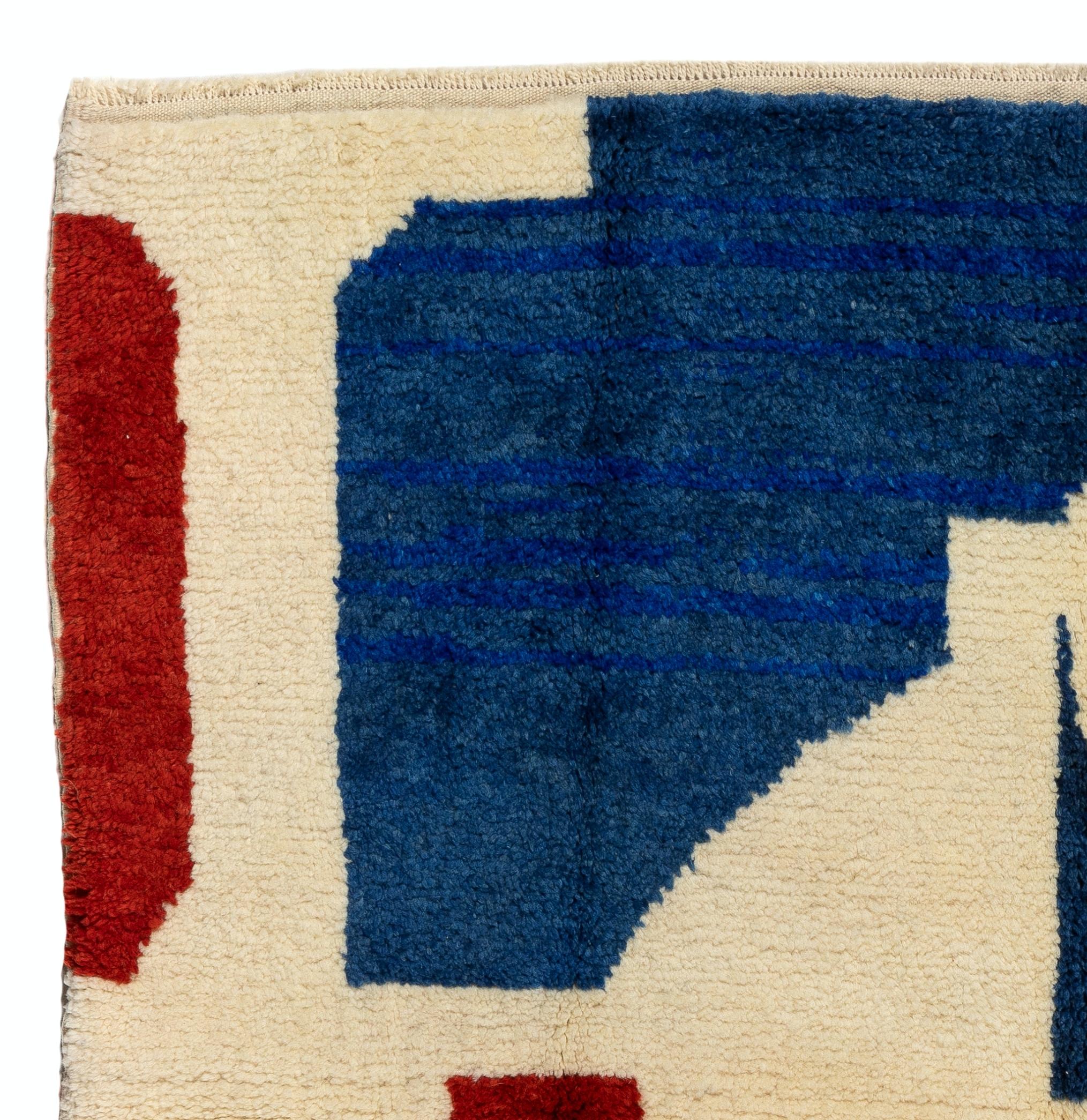 Un tappeto contemporaneo annodato a mano nei colori vivaci del blu, del rosso e del crema, con la parola 