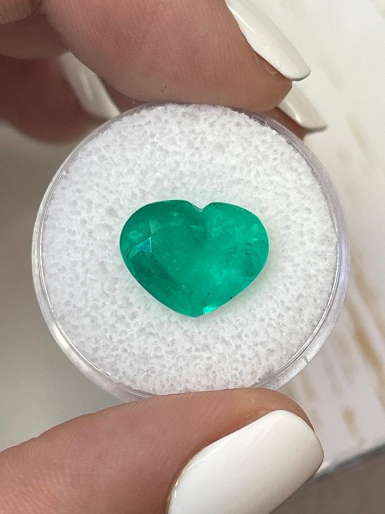 Stone: Emerald
Weight: 5.80-carats
Shape: Heart Cut
Clarity: Transparent
Luster: Very Good
Color: Medium Green
Measurements: 10.65mm x 13.62mm x 7.50mm
Geographic Origin: Colombia
Treatment: Natural, Oiling

Comments: Due to their growth conditions