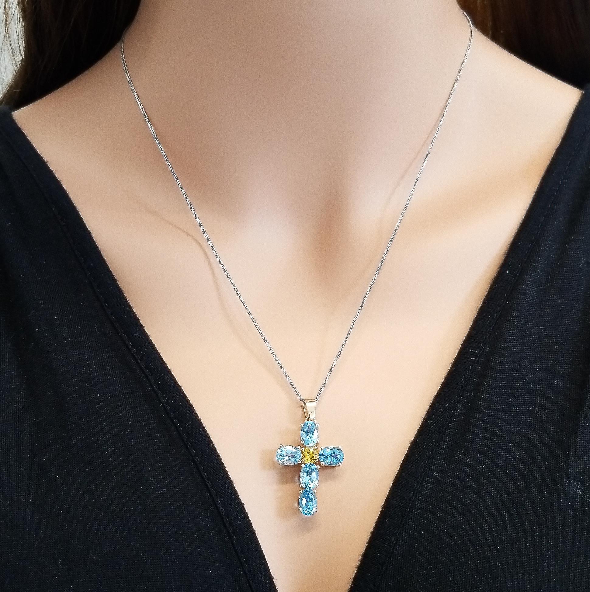 This is a vibrant, distinct gem Cross that will uplift you everytime. 5 Swiss blue topaz, oval cut, and one round cut intense orangey-yellow citrine garnet comprise this pendant. The gems' source is Brazil. Perfectly matched in color, size, luster