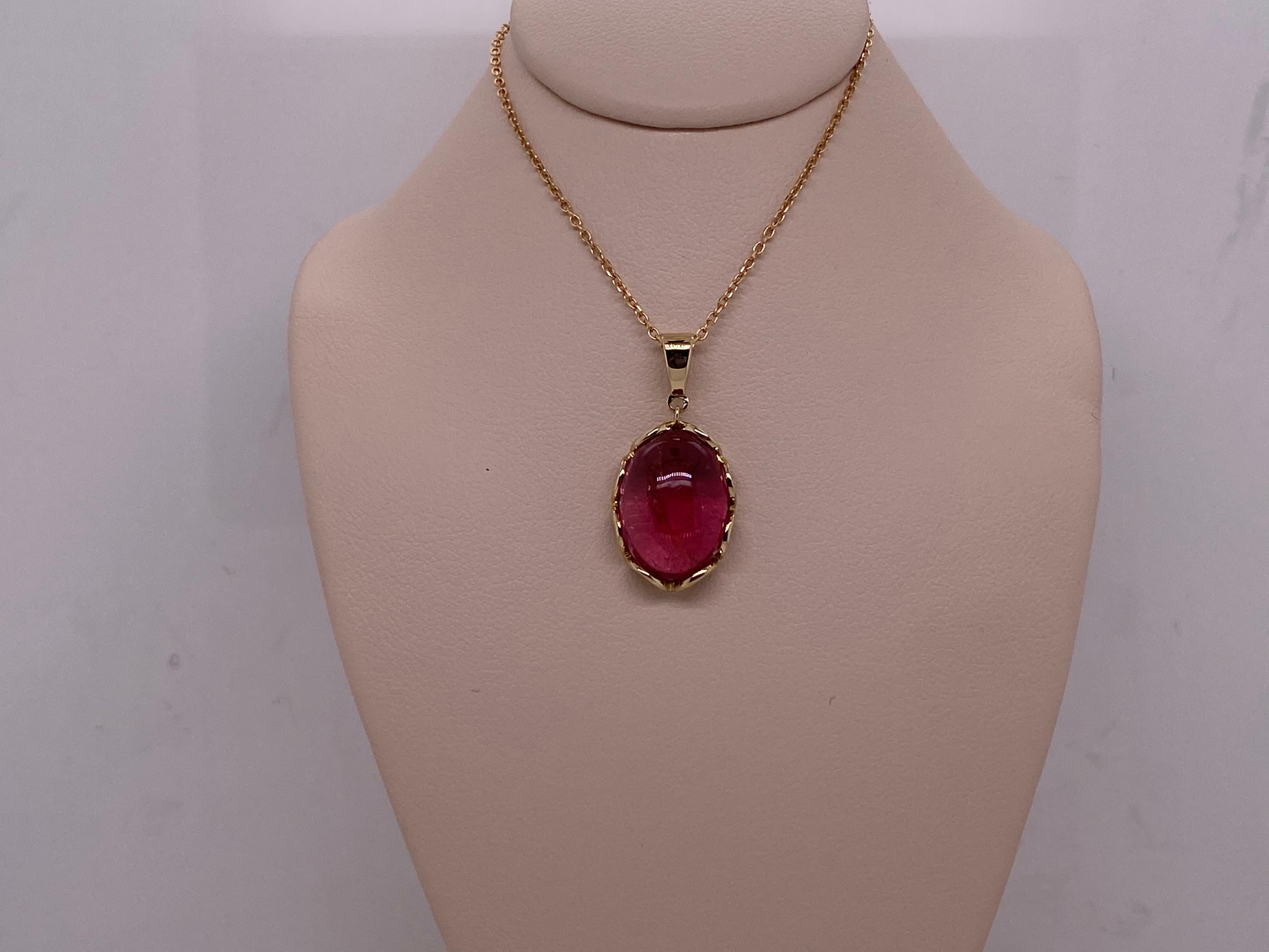 This necklace features a 5.81ct oval cabochon dark pink tourmaline set in a 14kt yellow gold pendant. The chain is 18 inches long.