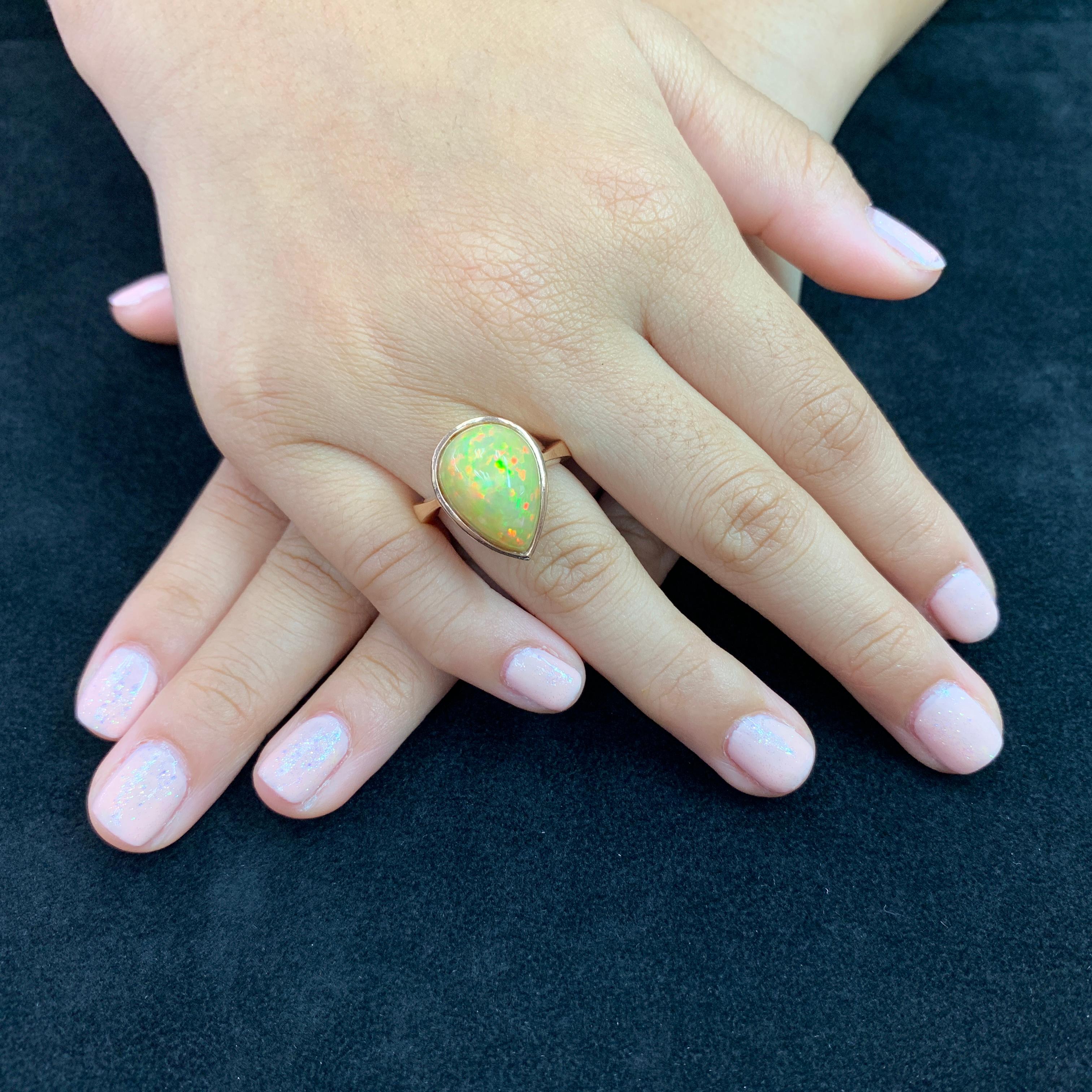 Here is a beautiful natural Opal (5.85 cts) ring. The ring is bezel set in 18k rose gold. The Opal is pear shaped. The color play in this Opal is exceptional. It is rare to have so much red (fire) and orange through out the opal. The color change