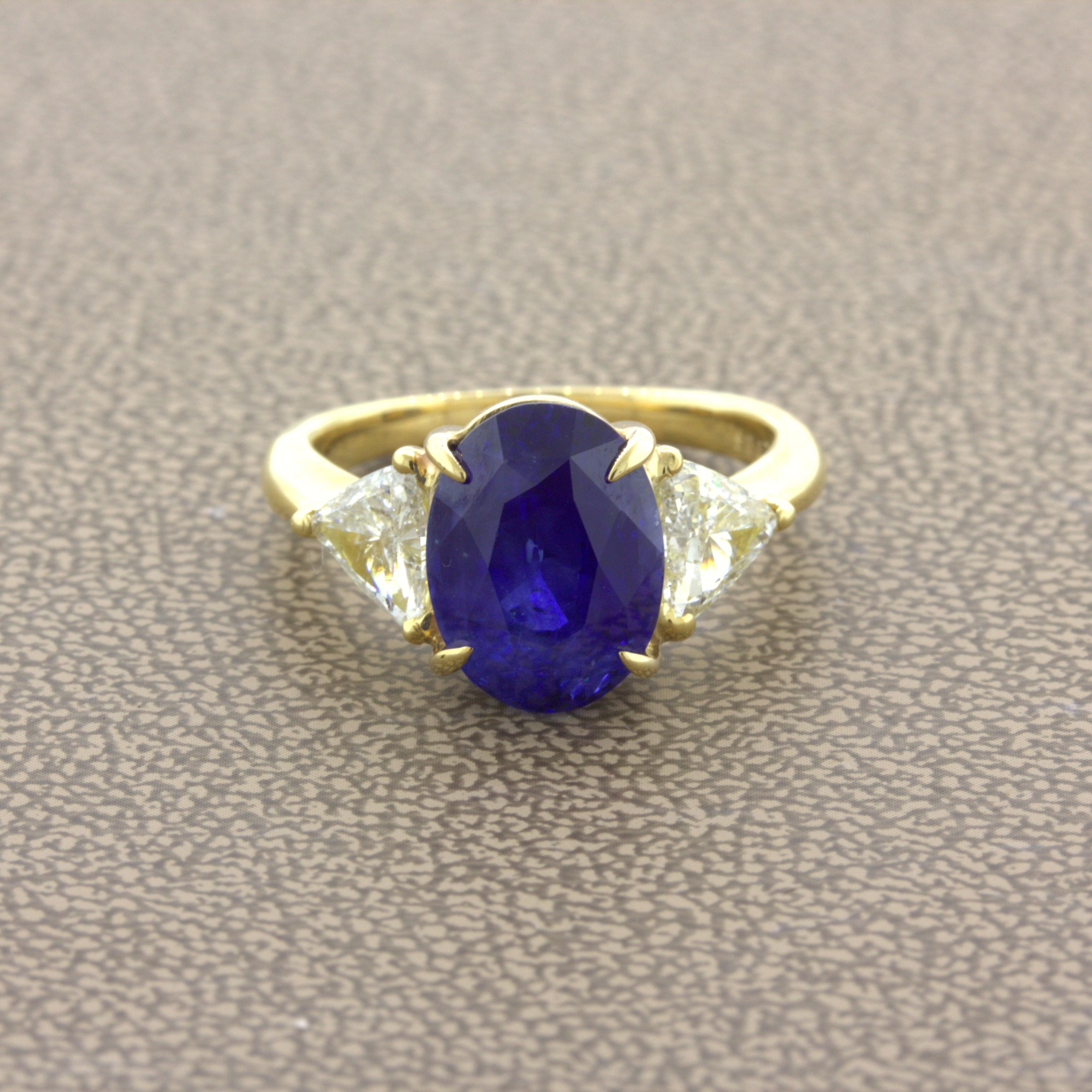 A rich and elegant blue sapphire weighing 5.87 carats takes center stage. The oval-shaped gem has a rich vivid blue color that glows in the light. We consider this fine color peacock blue for its intensity. It is complemented by two trillion-cut