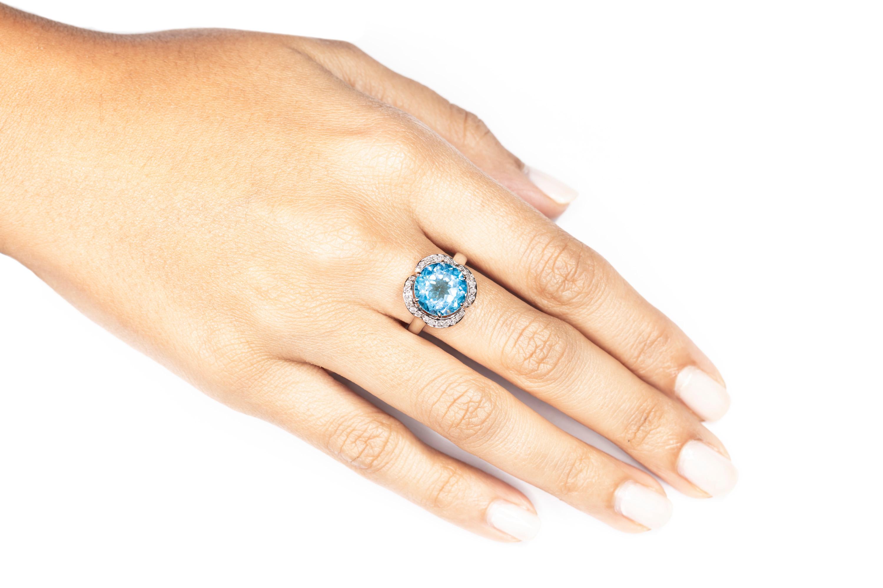 Butani's cocktail ring will carry you from occasion to event.  The ring features a center 5.88 carat round blue topaz surrounded by a halo of 0.29 carats of round brilliant-cut diamonds.  Currently a ring size US 7.  For other sizes, please contact