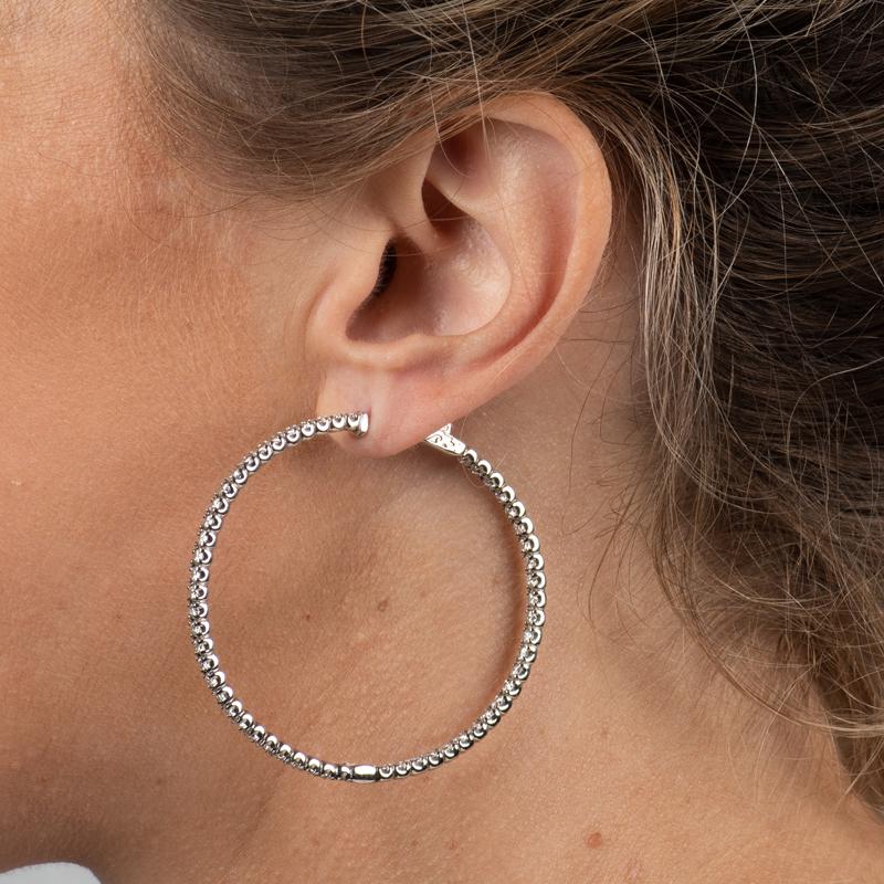 These hoop earrings feature 5.88 carat total weight in round natural diamonds set in 14 karat white gold. Locking mechanism. 
Measurements: Diameter approximately 50mm. Width approximately 2.85mm.
