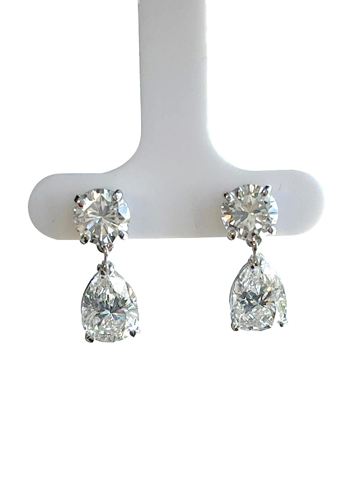 A Stunning Pair of 14K White Gold Pear Shape and Round Diamond Earrings. Each earring has a Pear Shape and Round cut diamond in a classic setting. Each Pear Shape diamond weights 1.92ct / 1.97ct with I / J colors and Si1 Clarity and Round diamond