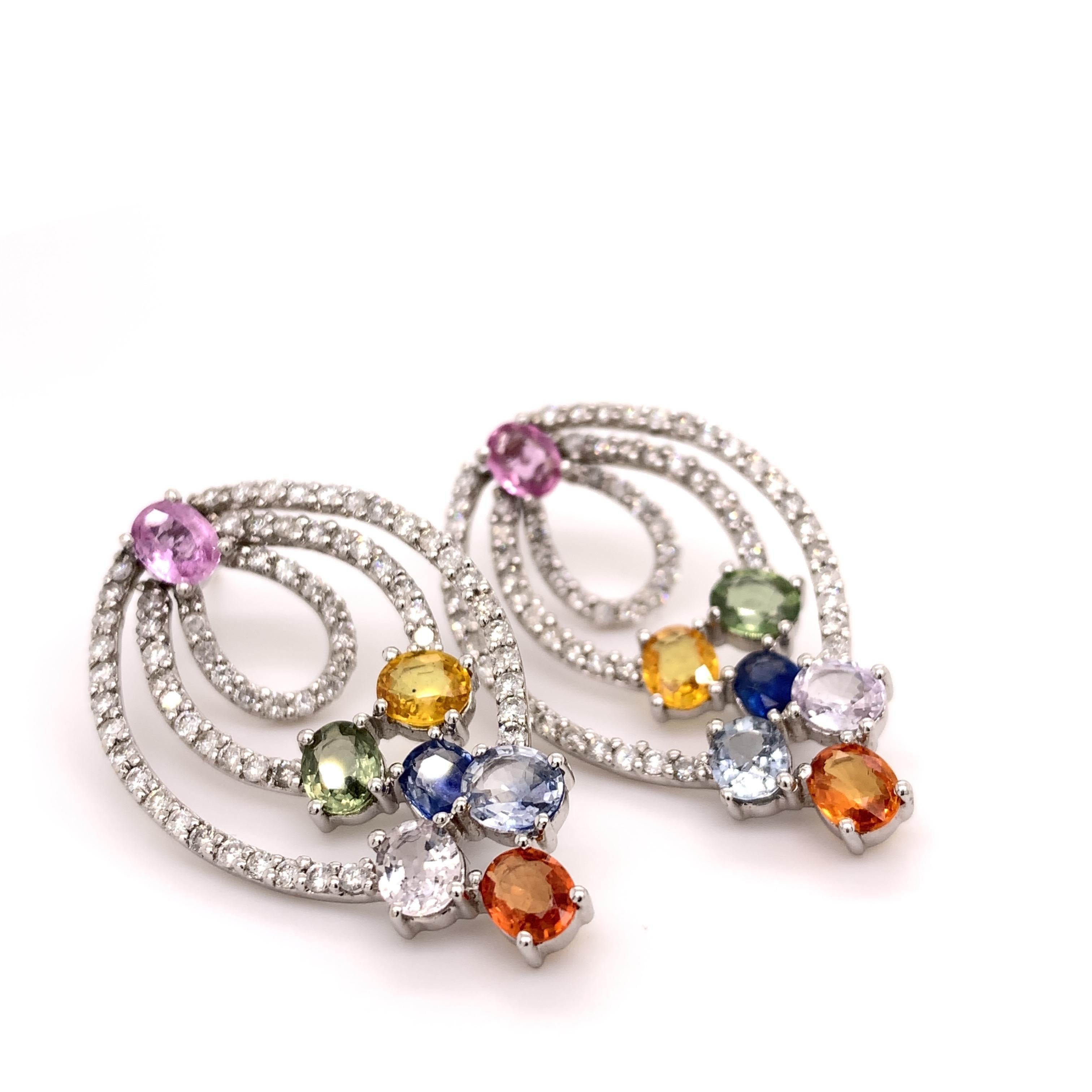 Glamorous multicolor sapphire diamond earrings. High brilliance, oval faceted, 5.89 carats multicolor natural sapphires earrings, accented with three dangling rows of round brilliant cut diamonds. Handcrafted design set in 14 karats white gold with