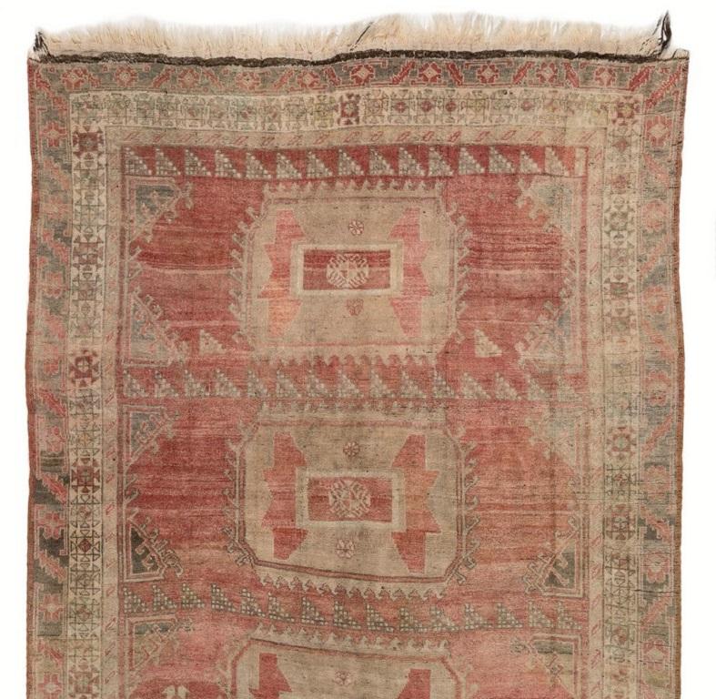 Alfombra turca vintage de Anatolia Central en suaves y estriados colores rojo rubí y beige piedra, con un diseño de extravagantes medallones geométricos múltiples. Finamente anudado a mano con pelo de lana medio uniforme sobre base de lana. Muy buen