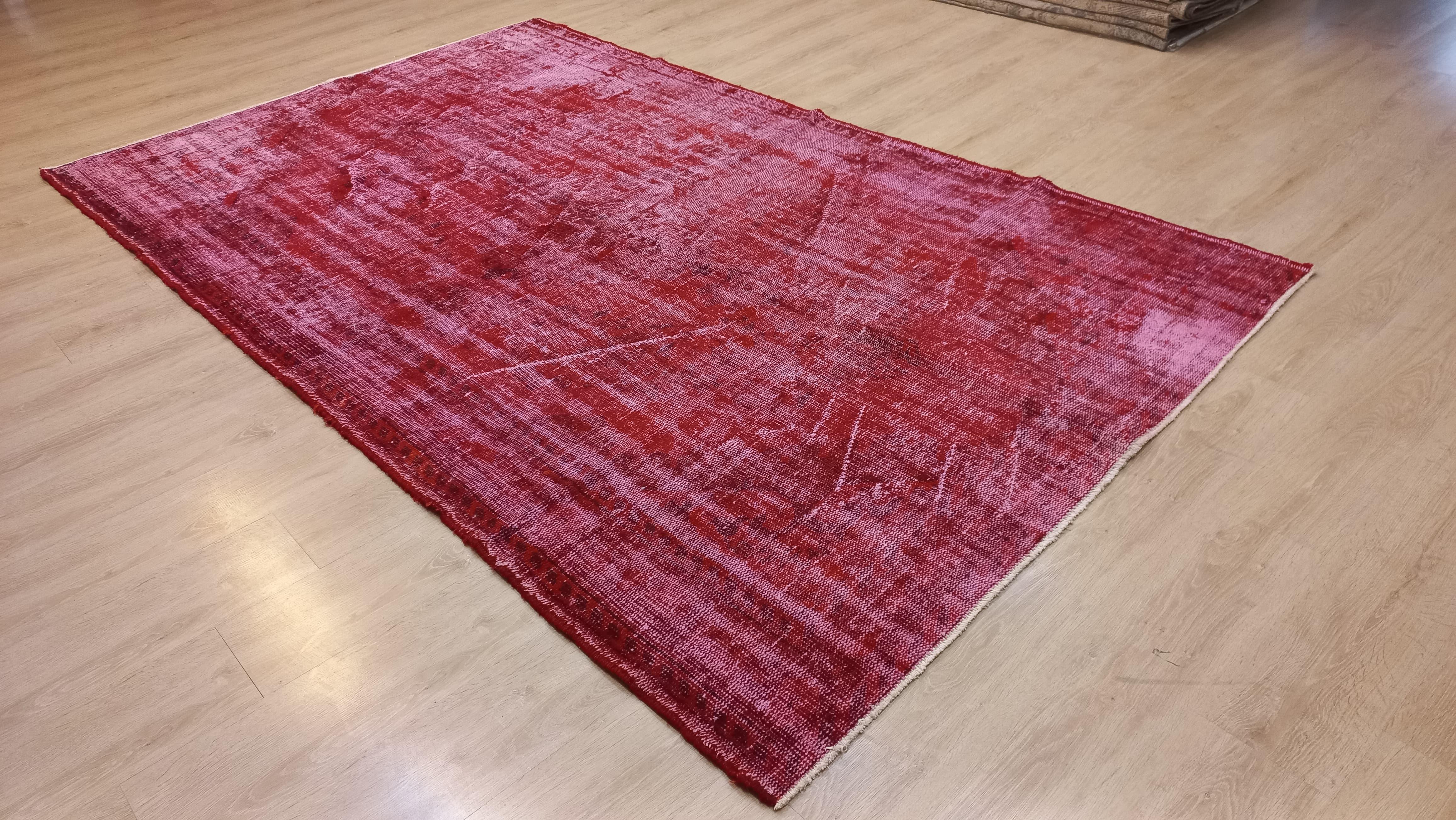 A handmade red re-dyed Turkish rug. Finely hand knotted, low wool pile on cotton foundation. 
Elevate your home with this unique blend of Shabby Chic allure and Turkish heritage, where the solid red over-dye transforms a vintage rug into a statement