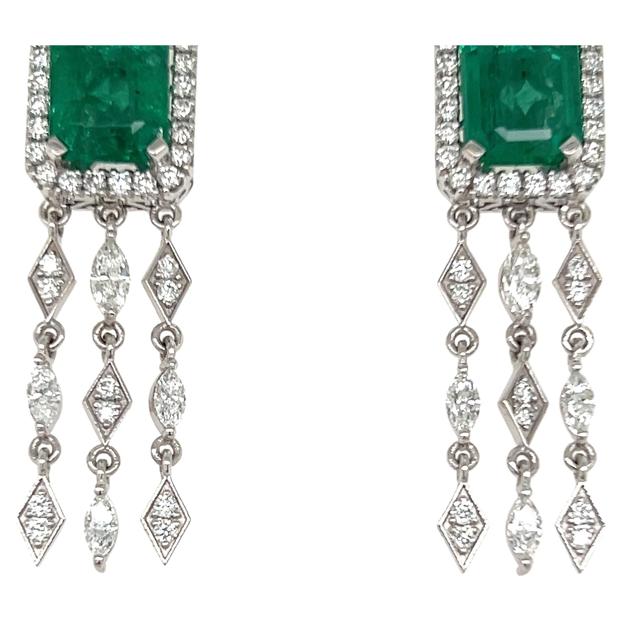 Glamorous dangling emerald earrings. High brilliance with rich grass green tone two matching 5.92 carat emerald cut natural emeralds encased in basket mounting with four bead prongs, accented with round brilliant cut diamonds. Handcrafted dangling