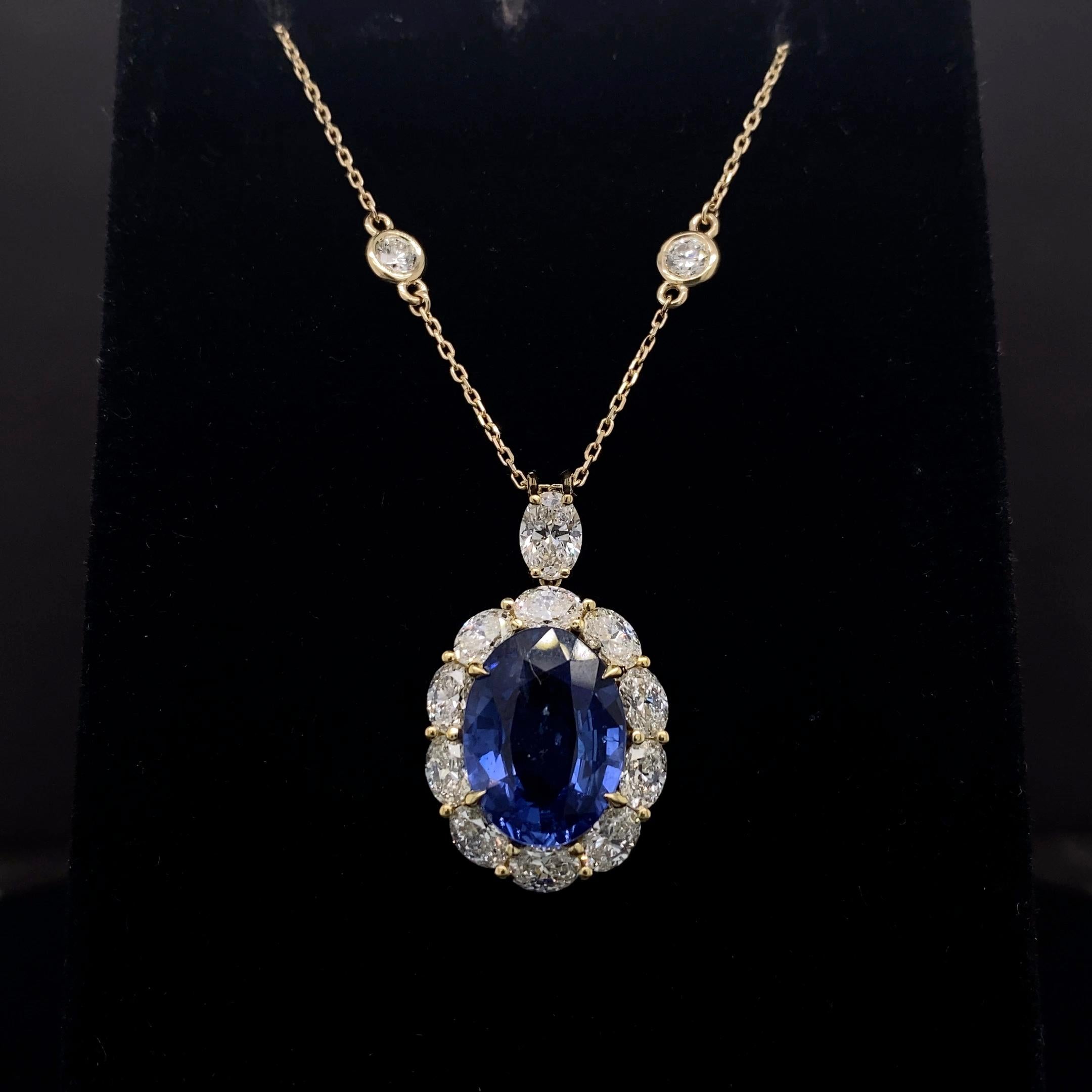 Collier pendentif classique mettant en valeur un saphir bleu de taille ovale pesant 5,94 carats au total. Elle est entourée d'une rangée de diamants ovales, pesant au total 3.25 carat. Suspendu à un halo de diamants de forme ovale, attaché à un