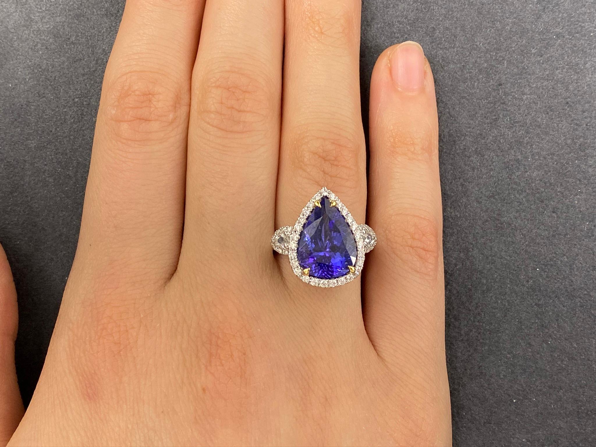 This stunning cocktail ring showcases a beautiful 5.94 Carat Pear Shape Tanzanite with a Diamond Halo. The Tanzanite is flanked by two Rose Cut White Diamonds, and sits on a Diamond Shank. This ring is set in 18k White Gold, with 18k Yellow Gold