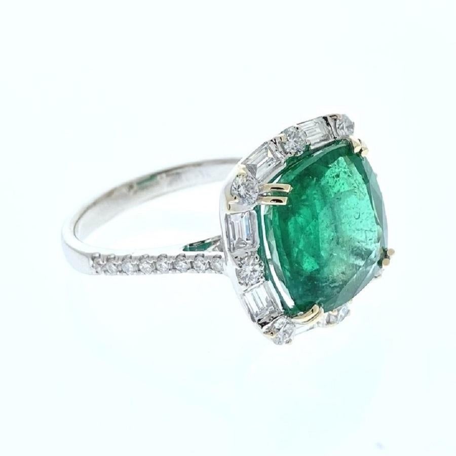This ring is a true testament to sophistication and grace. Crafted in 18 karat white gold, it showcases a stunning 5.96 carat cushion-shaped green emerald as its focal point. The emerald's deep, verdant hue is simply mesmerizing, radiating a