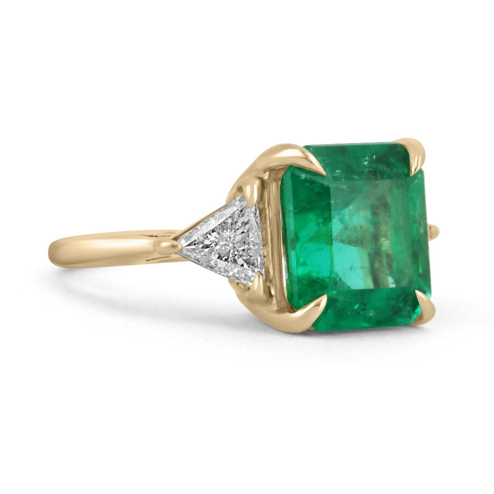 This is a grand AAA top-quality Colombian emerald and VS trillion diamond three-stone ring. Dexterously handcrafted in gleaming solid 18K gold this ring features a natural Colombian emerald from the famous Muzo mines. Set in a secure prong setting,