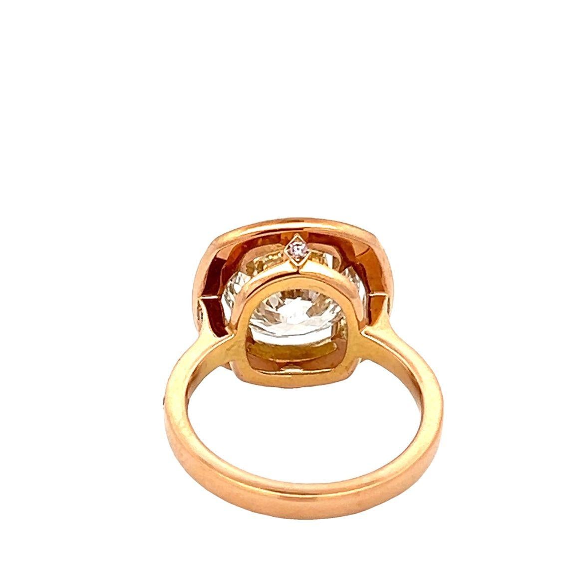 A fine 5ct premium cut round cut diamond is hand mounted in a 18 karat rose gold ring, with a single line border of fancy pink coloured diamonds weighing approximately 1.00 carat, framing the fiery scintillation of the centre diamond.  

The centre