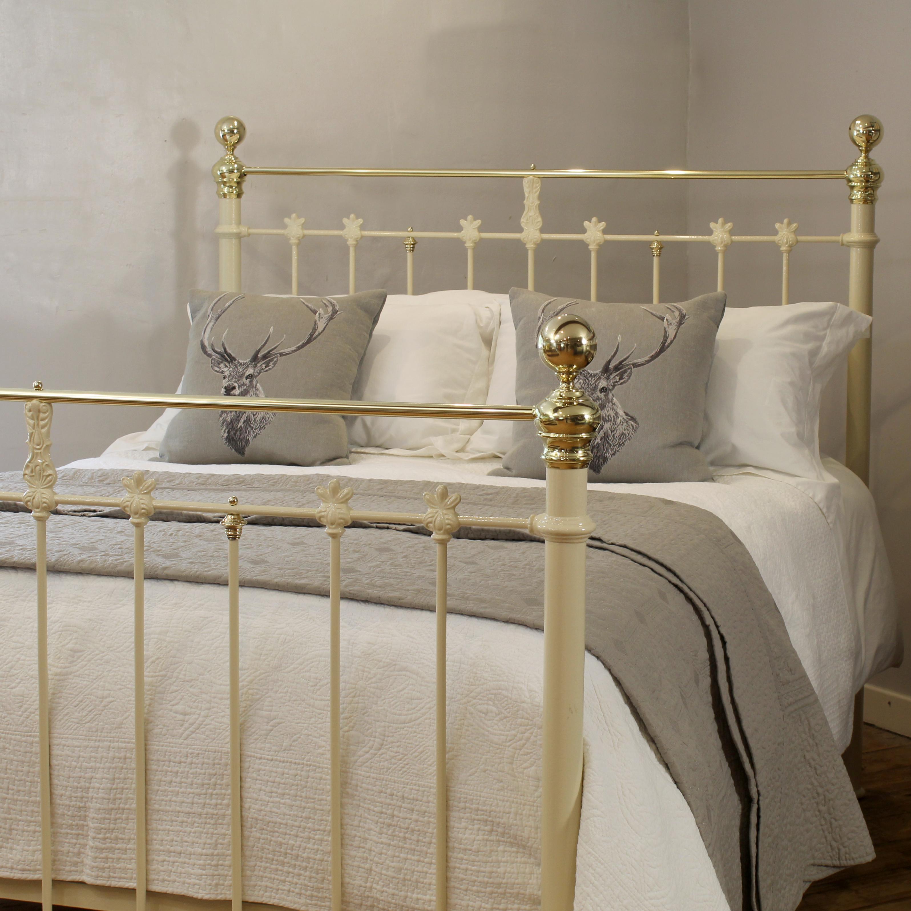 A late - Victorian brass and iron antique bed, circa 1890. Finished in a soft cream, this striking piece features straight polished brass top rails, traditional round brass knobs, and ornate decorative castings that capture the charm and