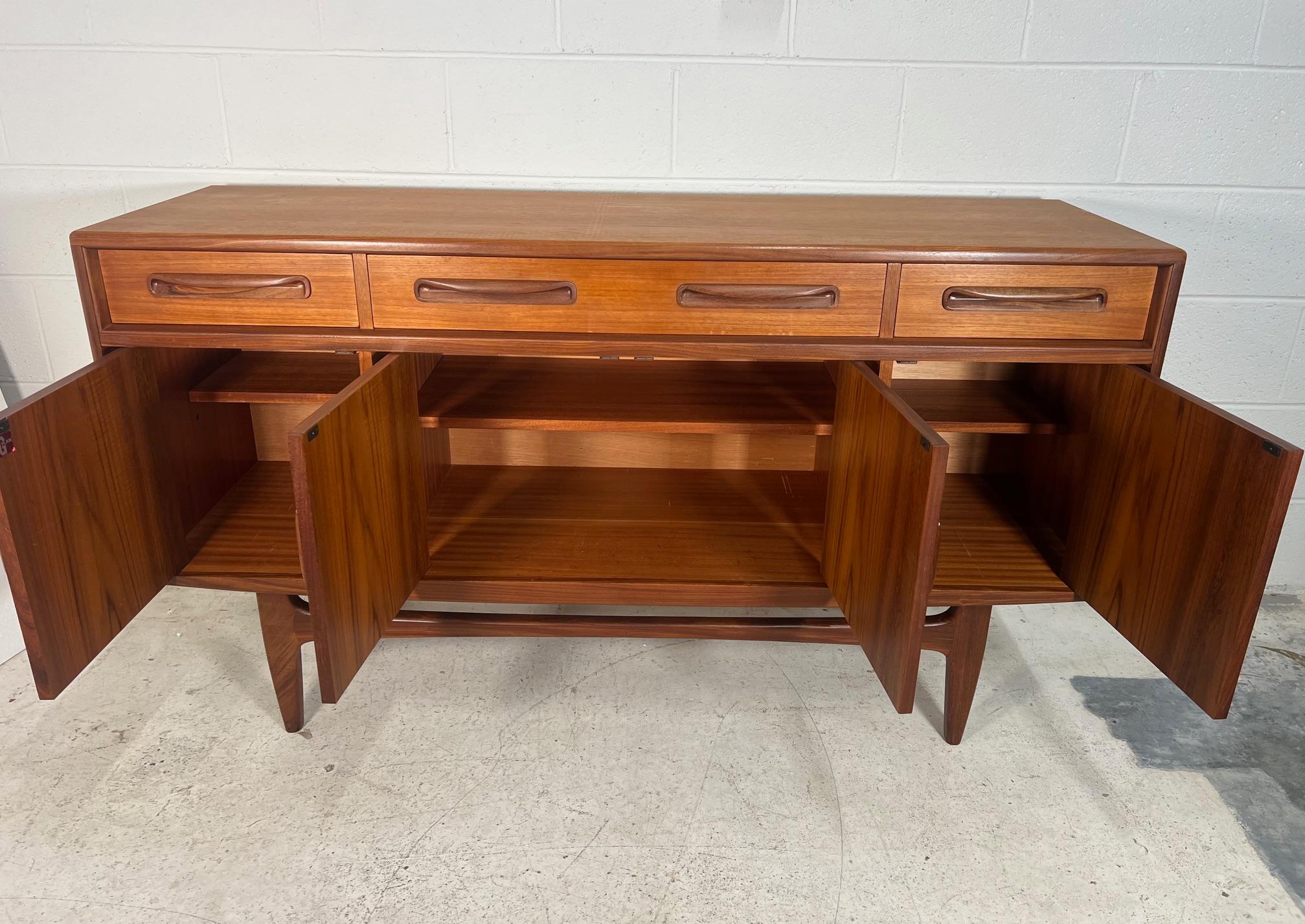 Outstanding small teak credenza. It was designed in the 1960s by Victor Bramwell Wilkins for G Plan's Fresco Range. It has original grey baize and wood dividers in the top drawer. Adjustable shelves inside the cabinets.
The back is unfinished.
Very